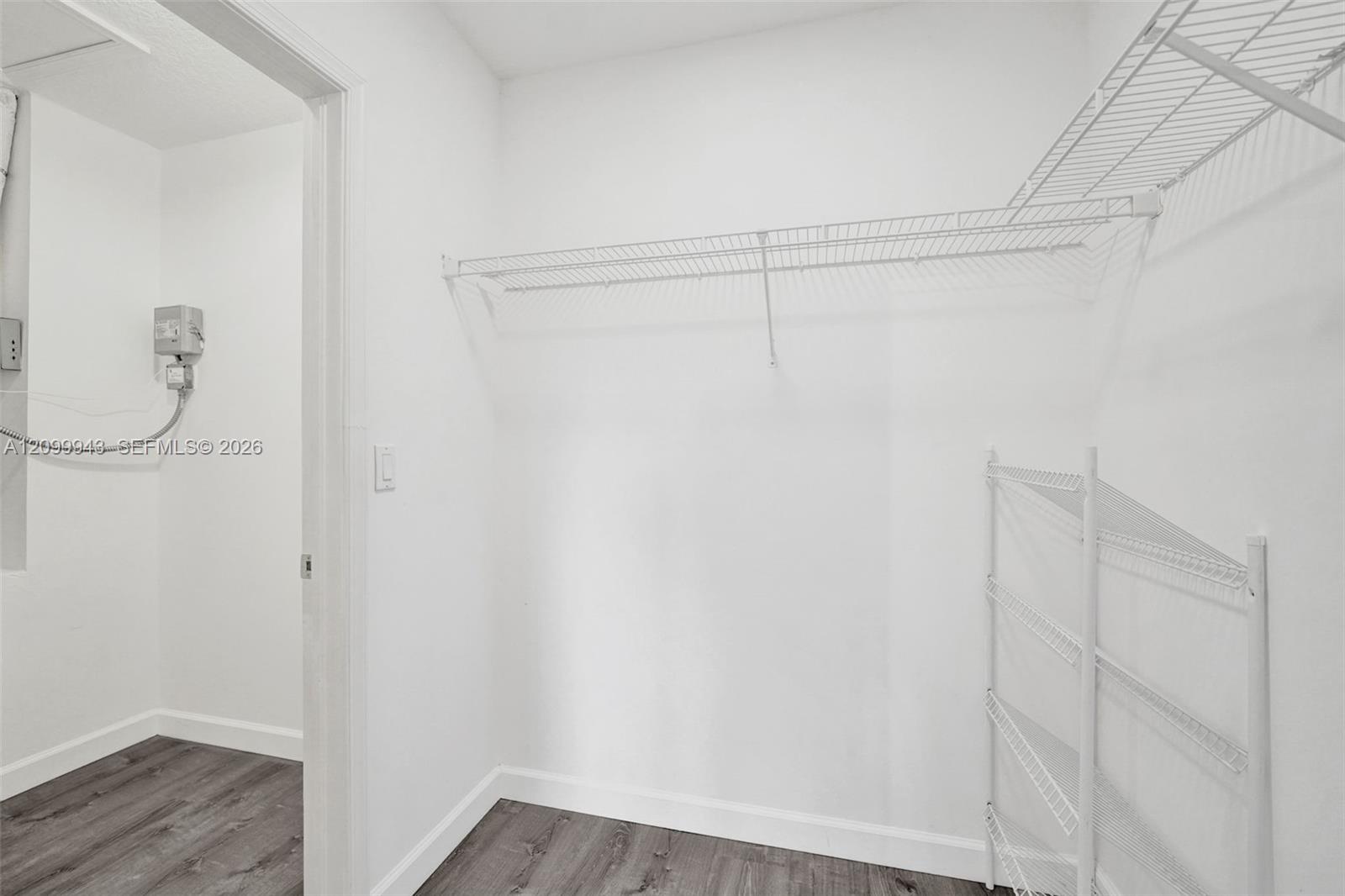 Walk-in storage area featuring wood-finish flooring and integrated white wire shelving systems