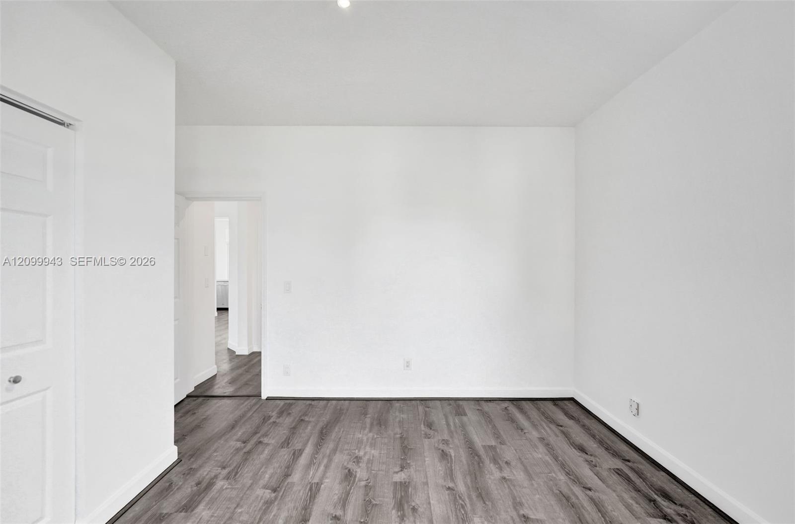 Interior space featuring wood-finish flooring, crisp white wall finishes, and a traditional-style interior door
