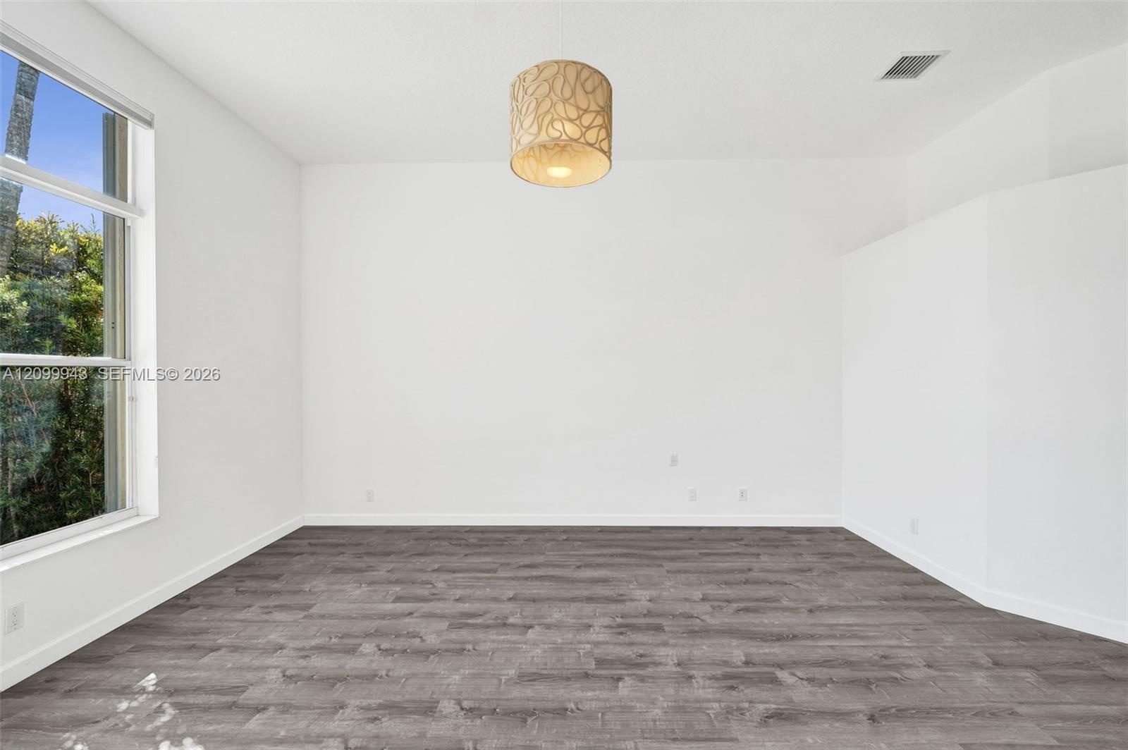 Neutral interior featuring wood-finish flooring, a large multi-pane window, and a drum-style pendant light fixture
