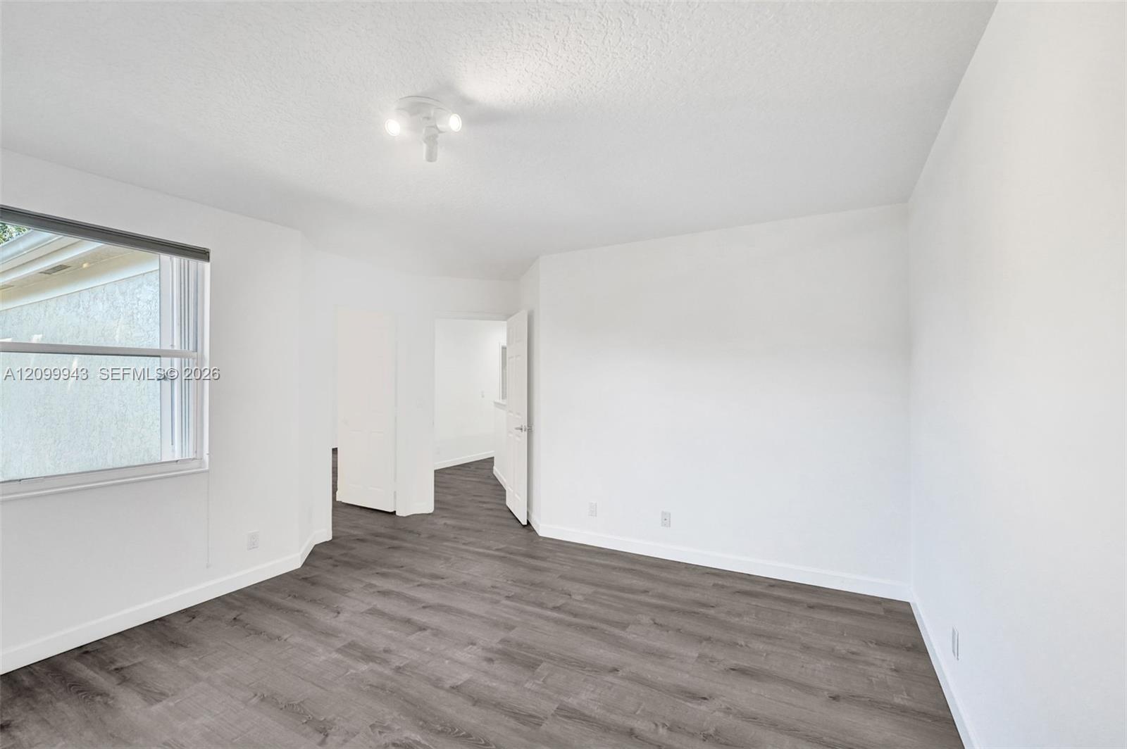 Interior space featuring wood-finish flooring, white walls, and a multi-bulb flush-mount ceiling fixture