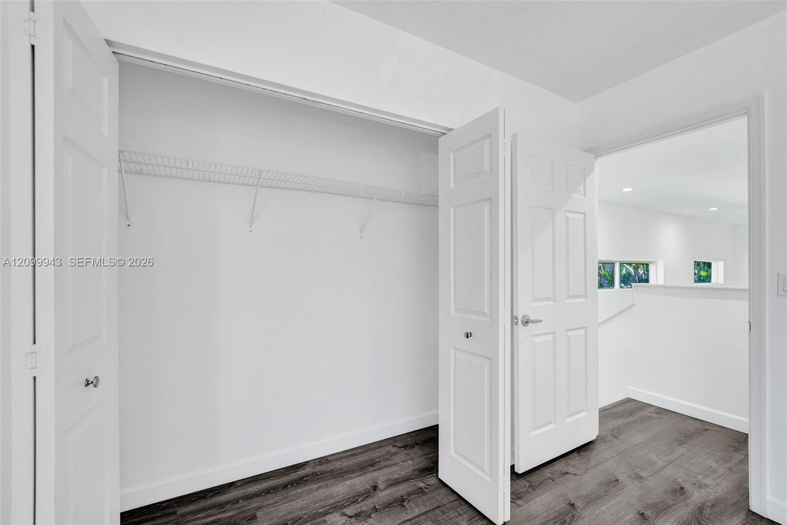 Interior closet featuring white paneled bifold doors, wire shelving, and wood-finish flooring