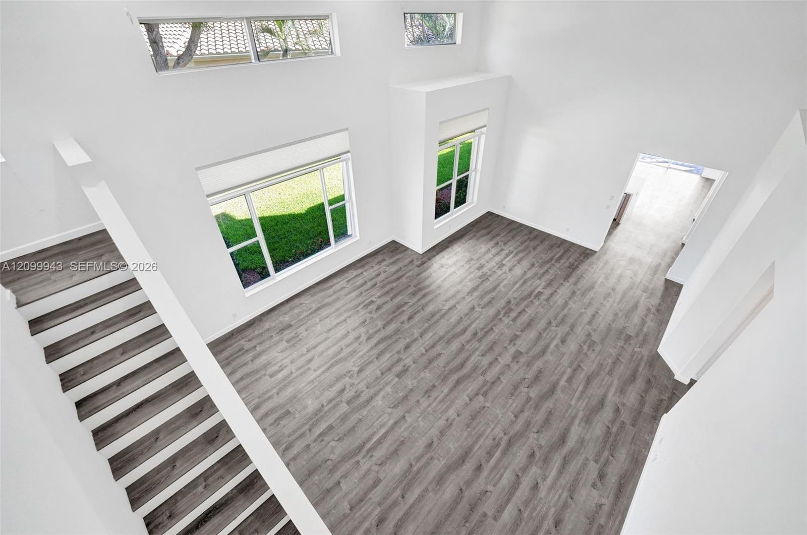 Vaulted ceilings featuring clerestory windows, wood-finish flooring, and expansive windows