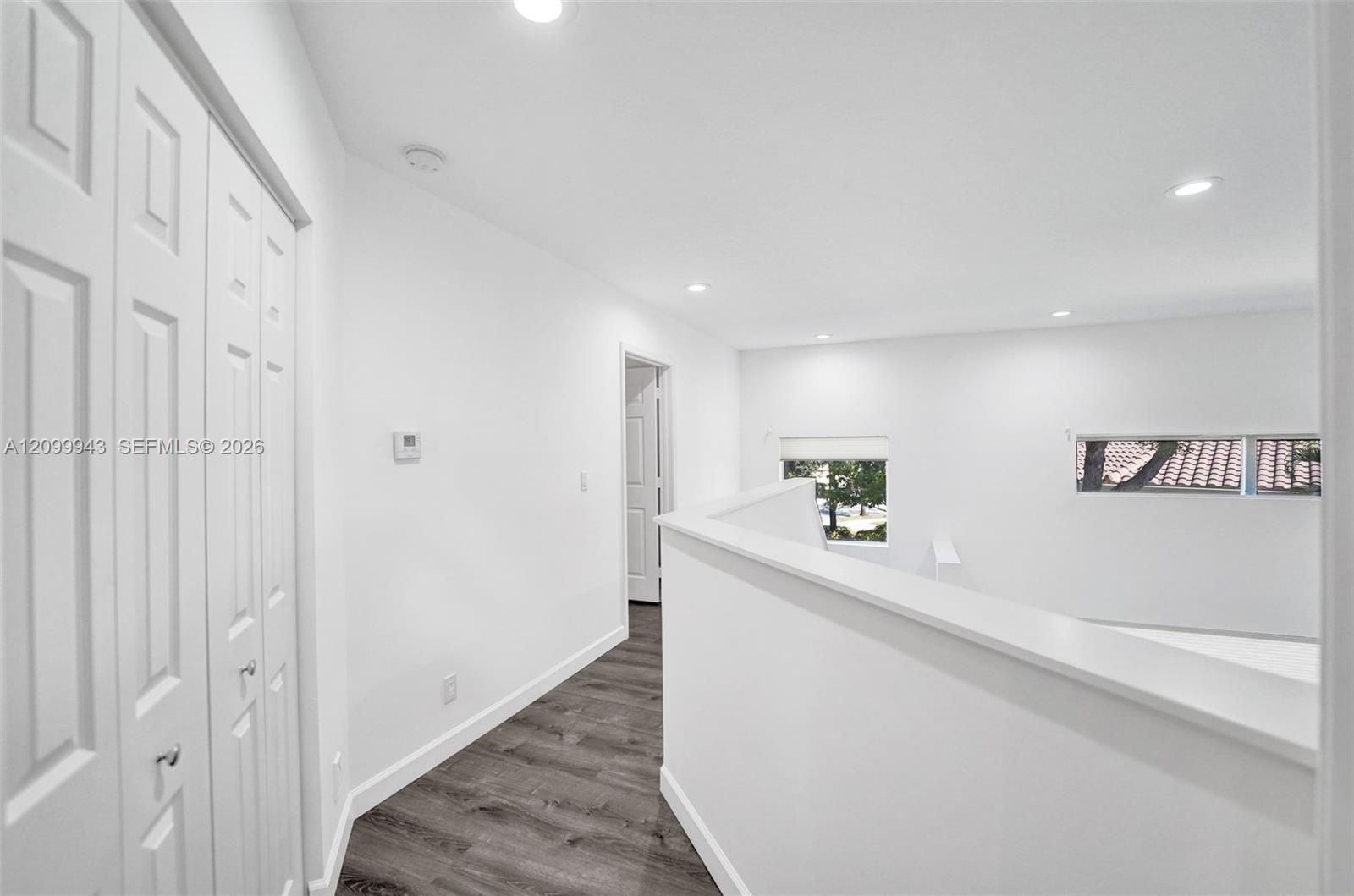 Hallway featuring wood-finish flooring, recessed lighting, and a white bi-fold closet door