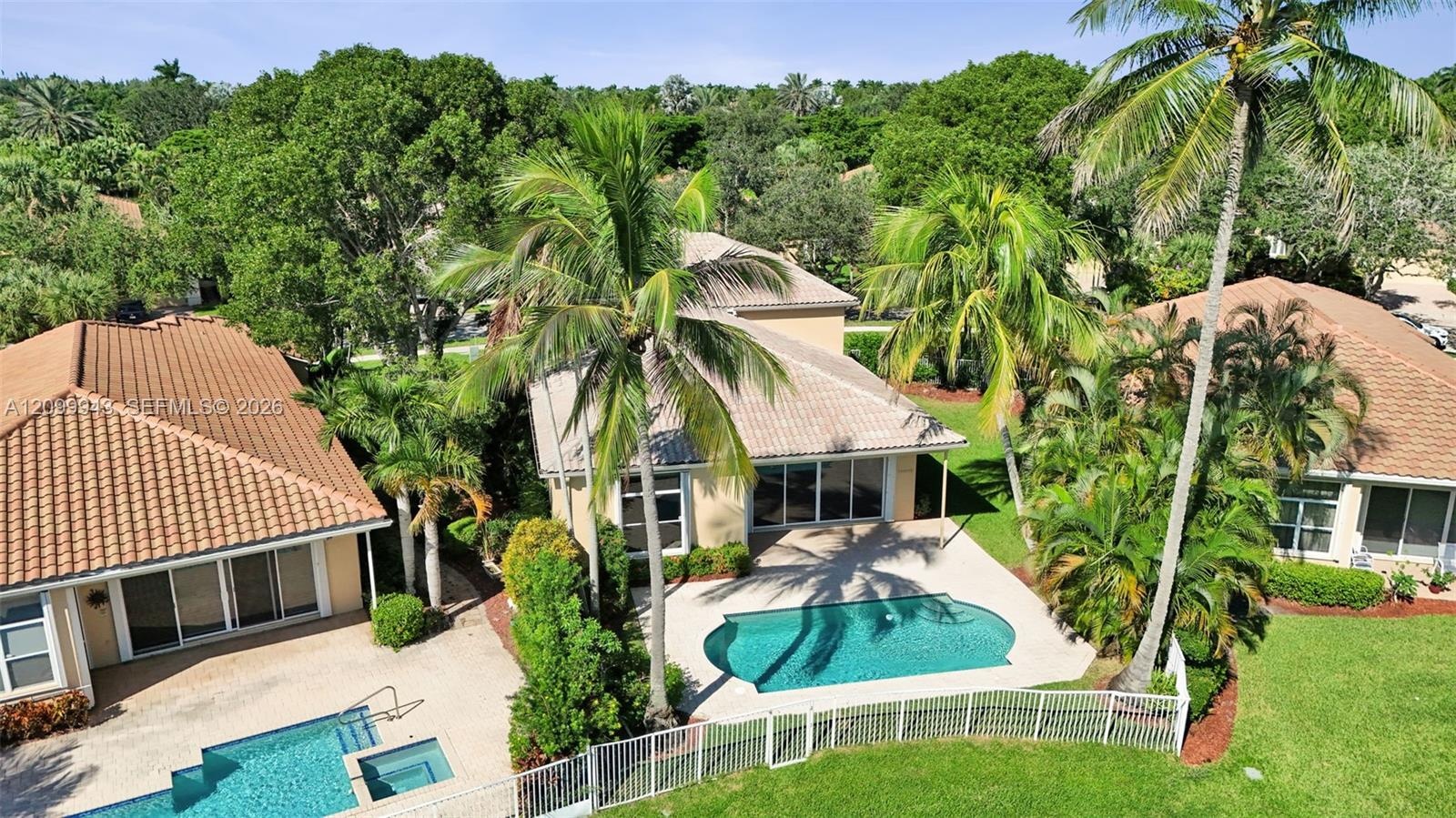 Stucco exterior residence featuring a tile roof, private swimming pool, patio area, and mature landscaping