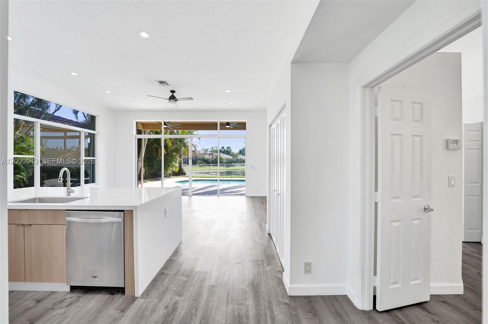 Kitchen area featuring a quartz countertop island, stainless steel dishwasher, wood-finish flooring, recessed lighting, and expansive glass sliding do