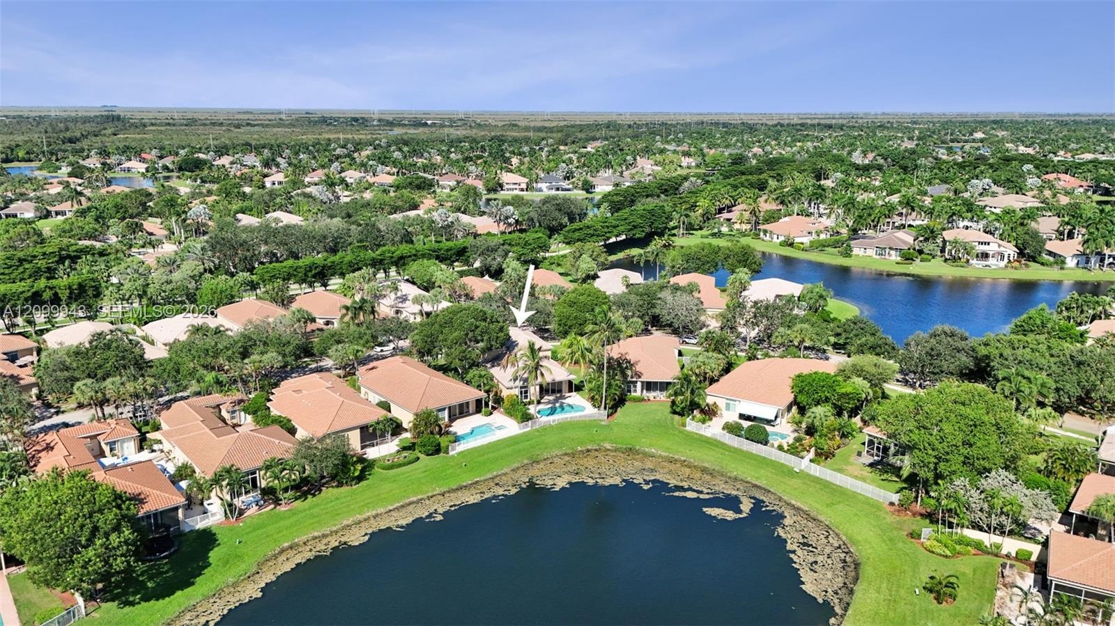 Aerial perspective of a property featuring a swimming pool, screened-in lanai, and waterfront positioning on a lake