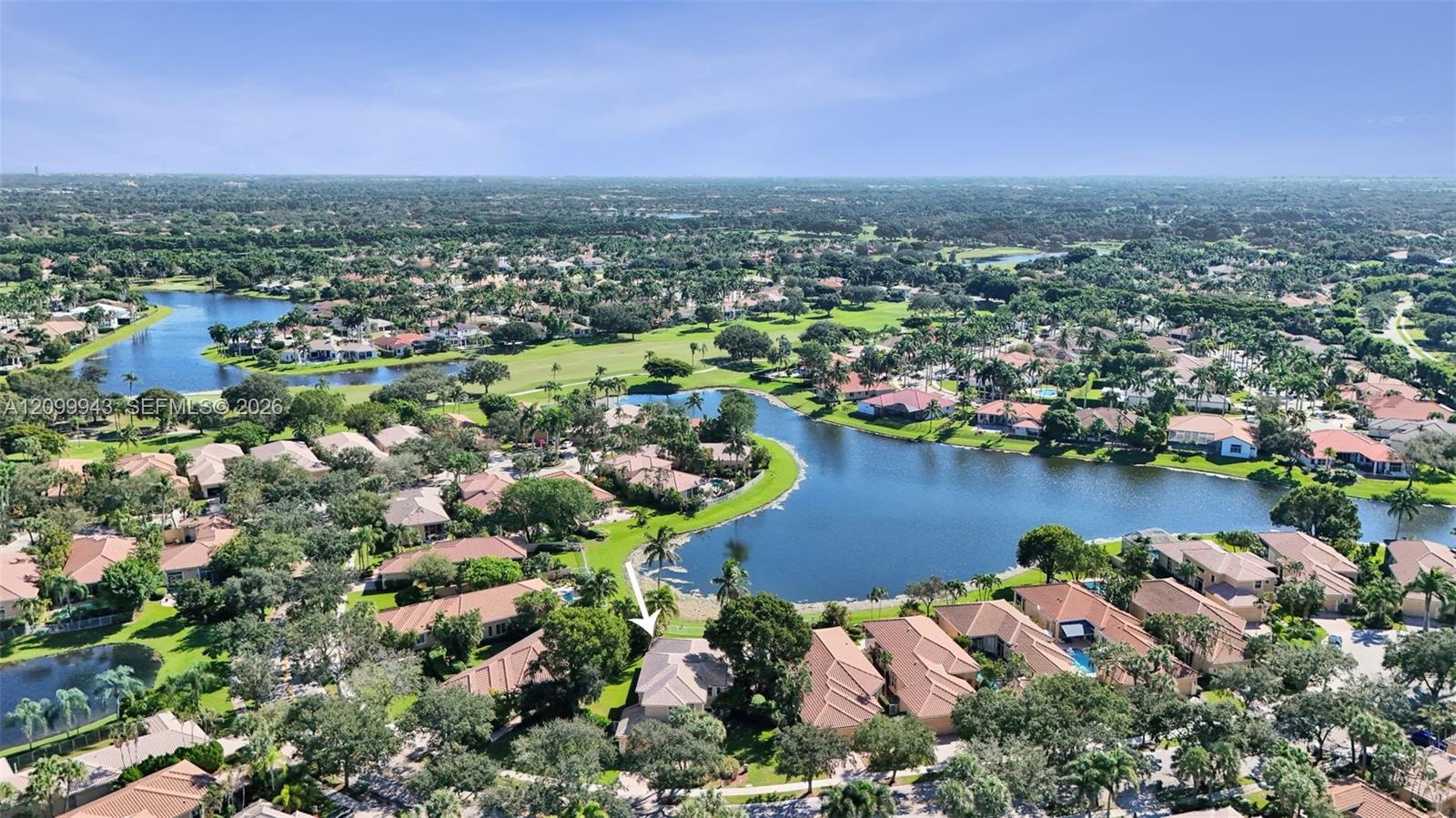 Aerial perspective of a property featuring a tile roof, mature landscaping, and positioning along a lakefront