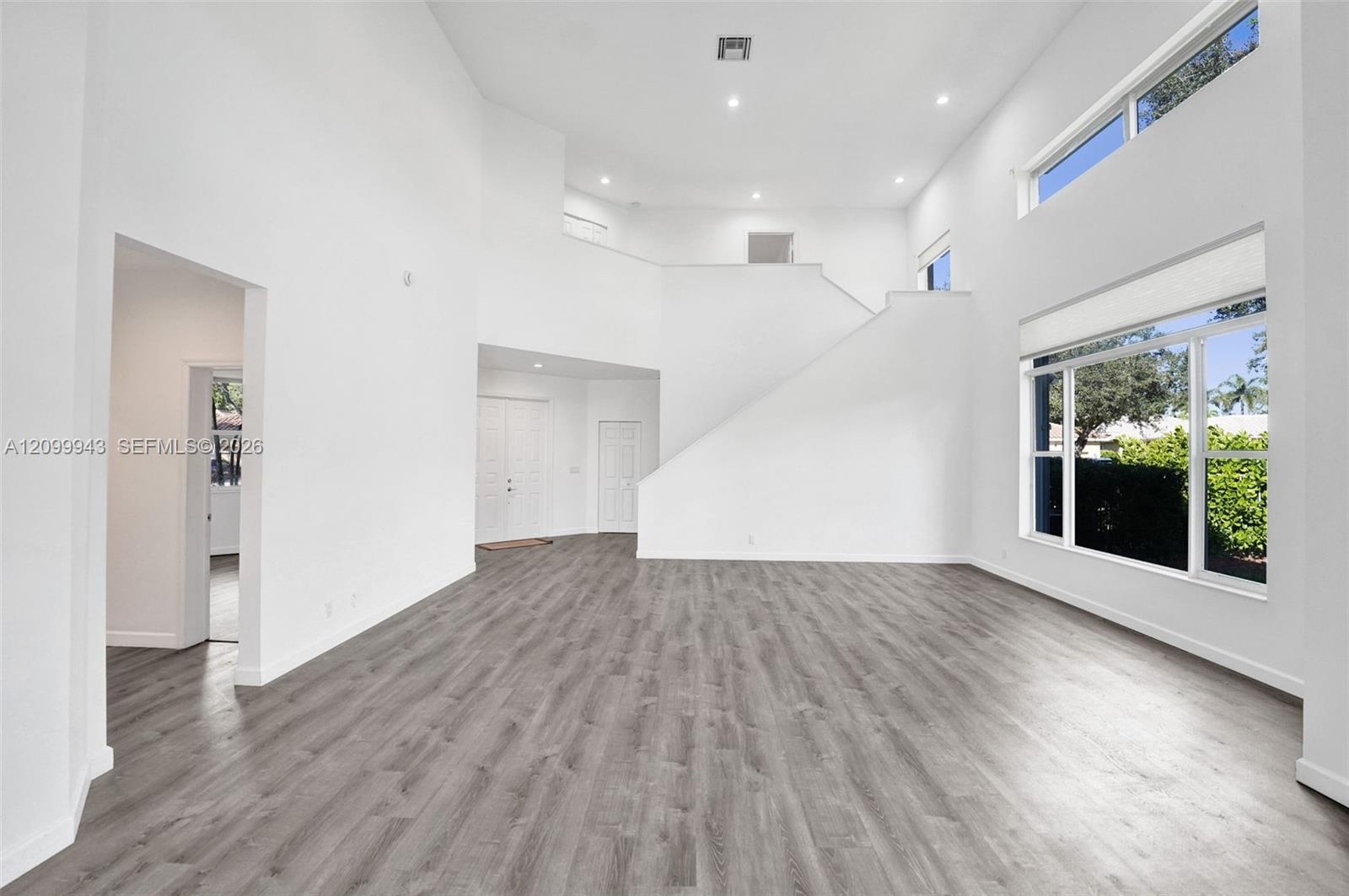 Vaulted ceilings, wood-finish flooring, recessed lighting, multi-level windows, and a staircase with a solid partition wall