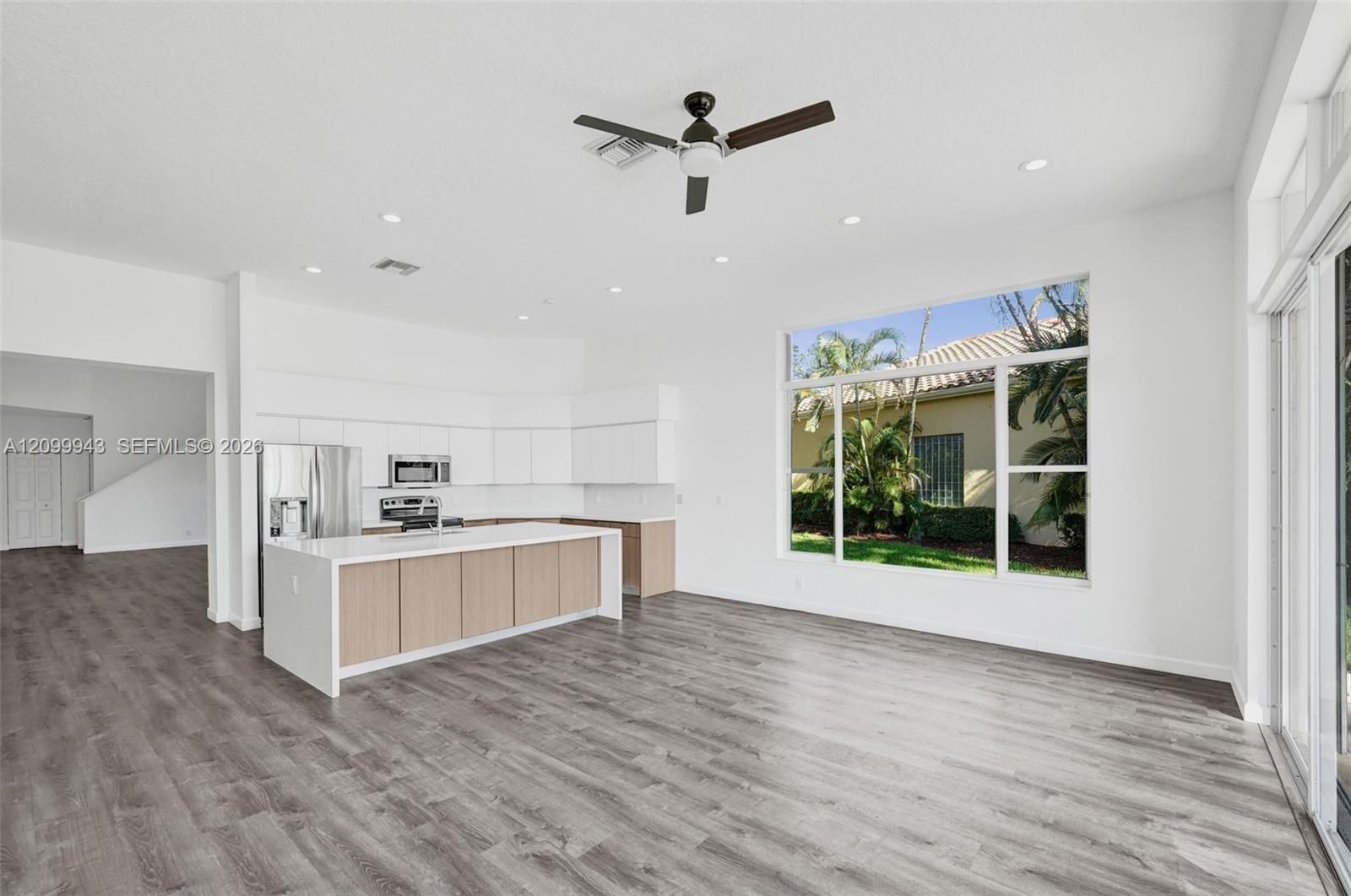 Open-concept interior featuring wood-finish flooring, recessed lighting, a ceiling fan, and a kitchen island with white countertop and wood-finish cab