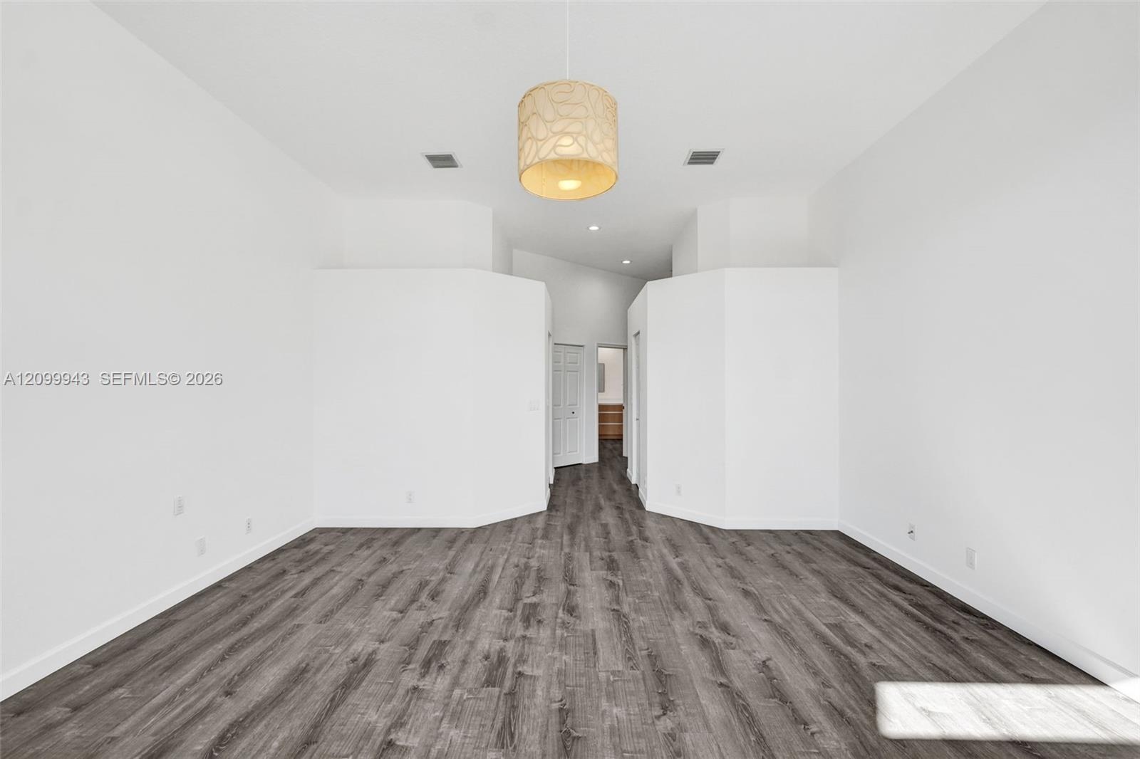 Room featuring high vaulted ceilings, wood-finish flooring, and a textured drum pendant light fixture