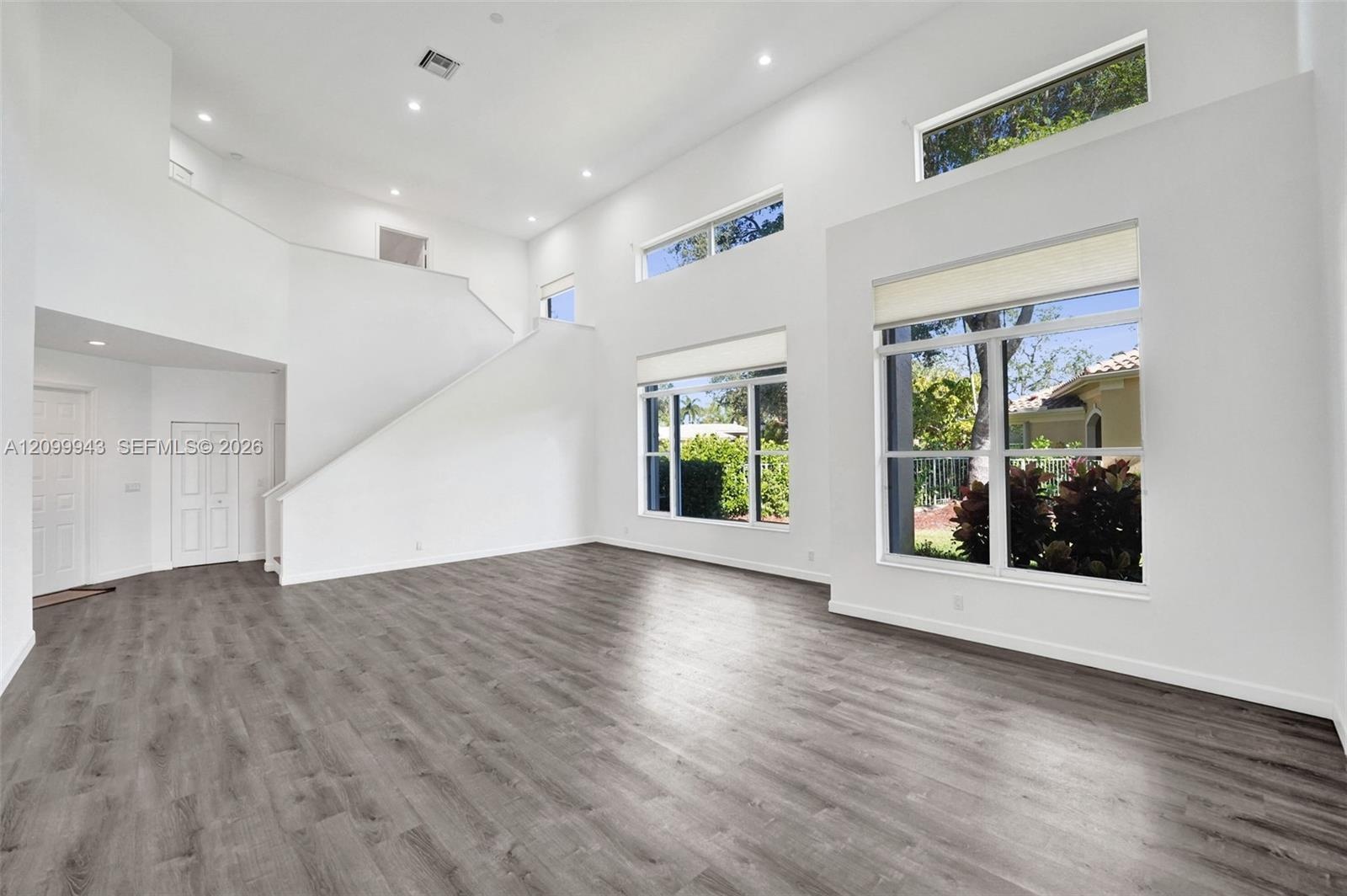 High-ceilinged interior featuring wood-finish flooring, recessed lighting, and multi-level windows