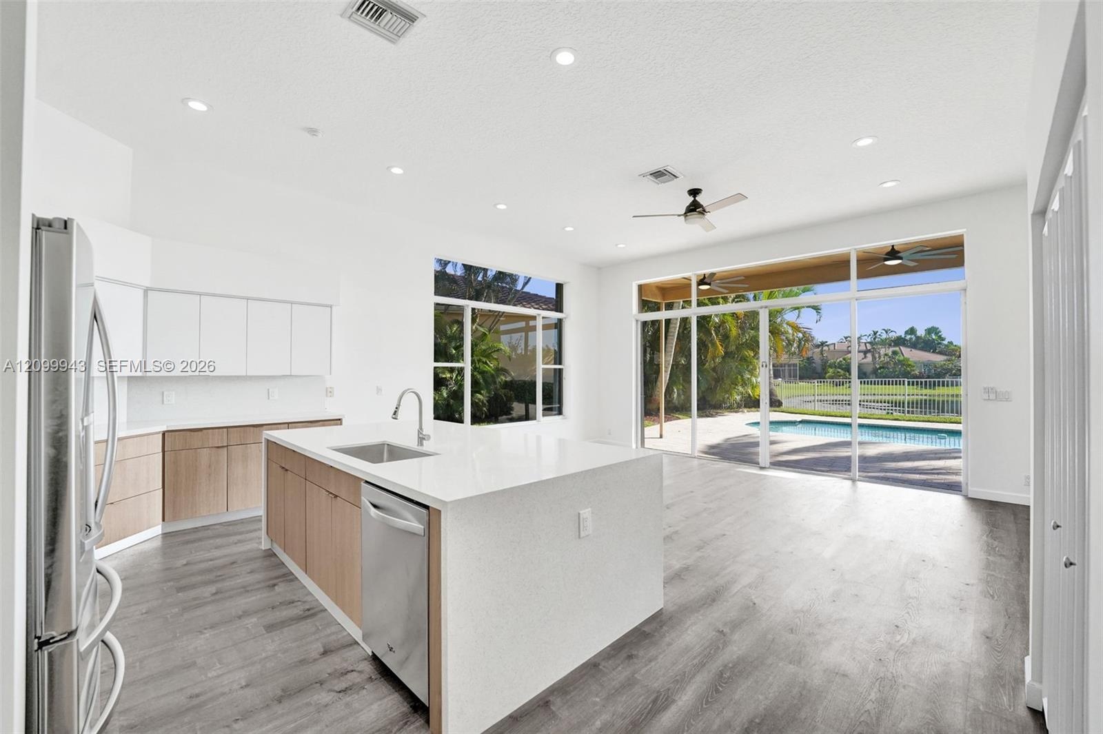Kitchen featuring wood-finish cabinetry, white countertops, stainless steel appliances, wood-finish flooring, and expansive glass sliding doors