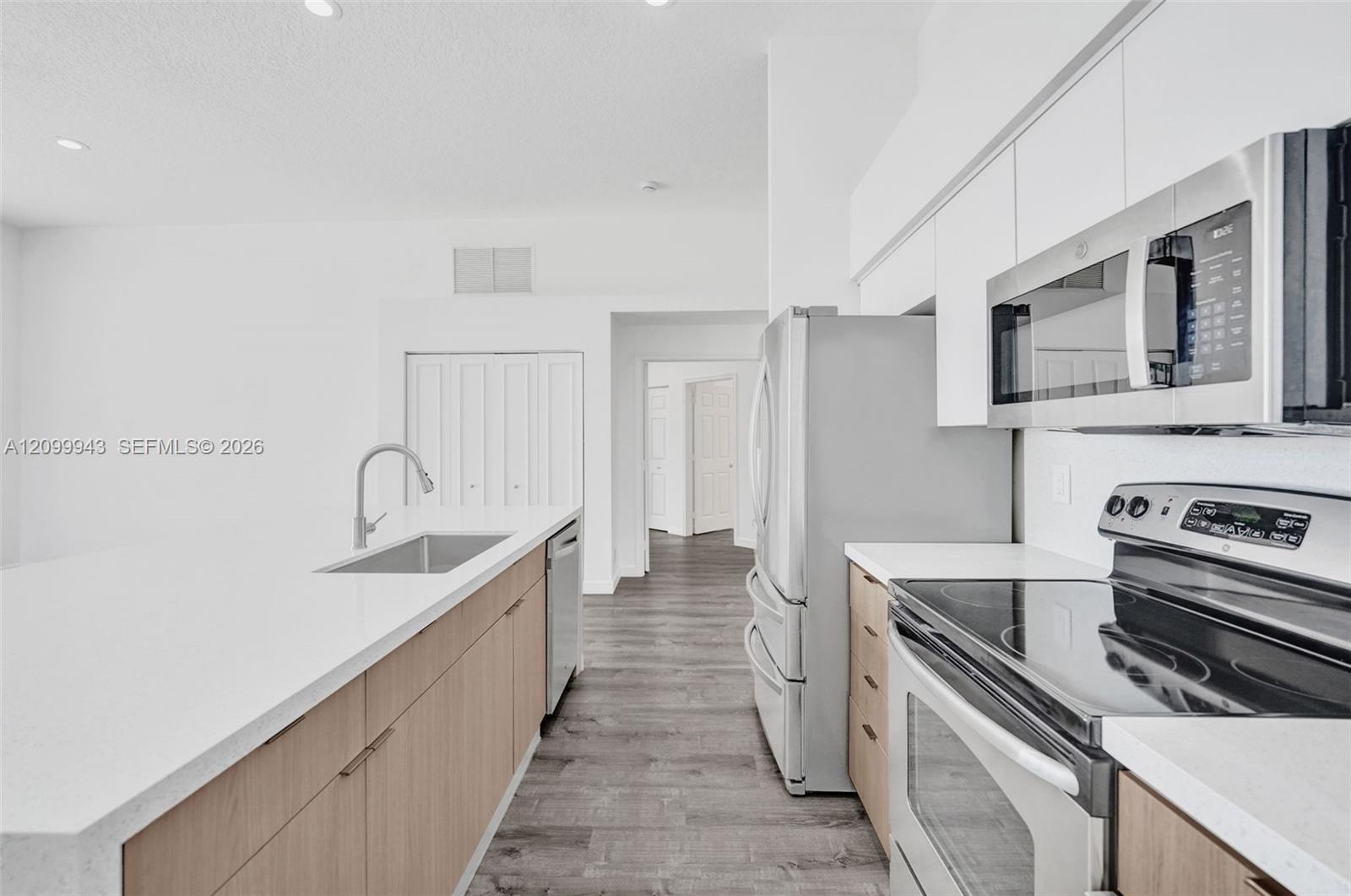 Kitchen featuring wood-finish cabinetry, white countertops, stainless steel appliances, and wood-finish flooring