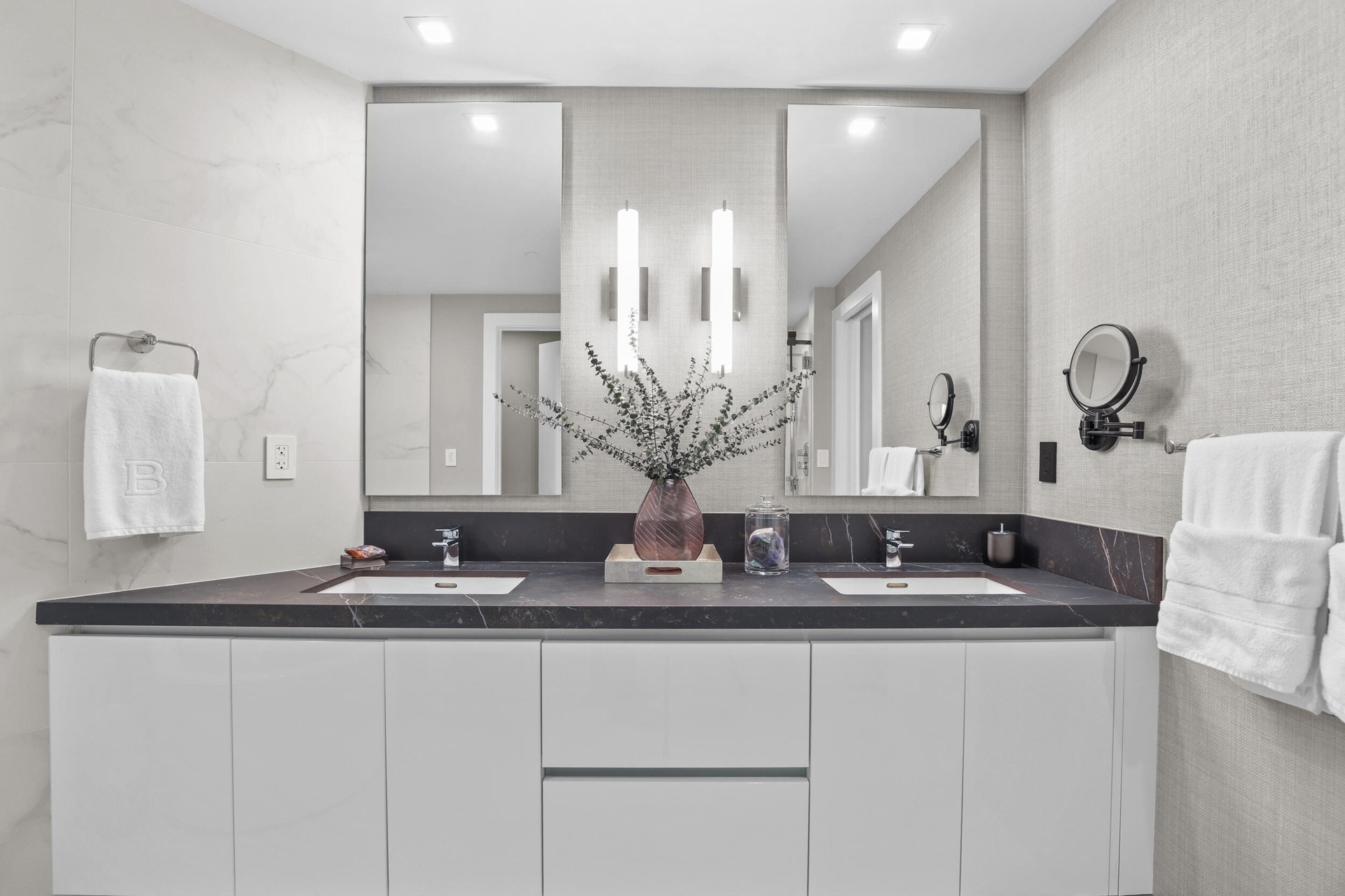 A private spa within the primary suite, this exquisite bathroom showcases custom porcelain tile, a frameless glass shower, a freestanding soaking tub 