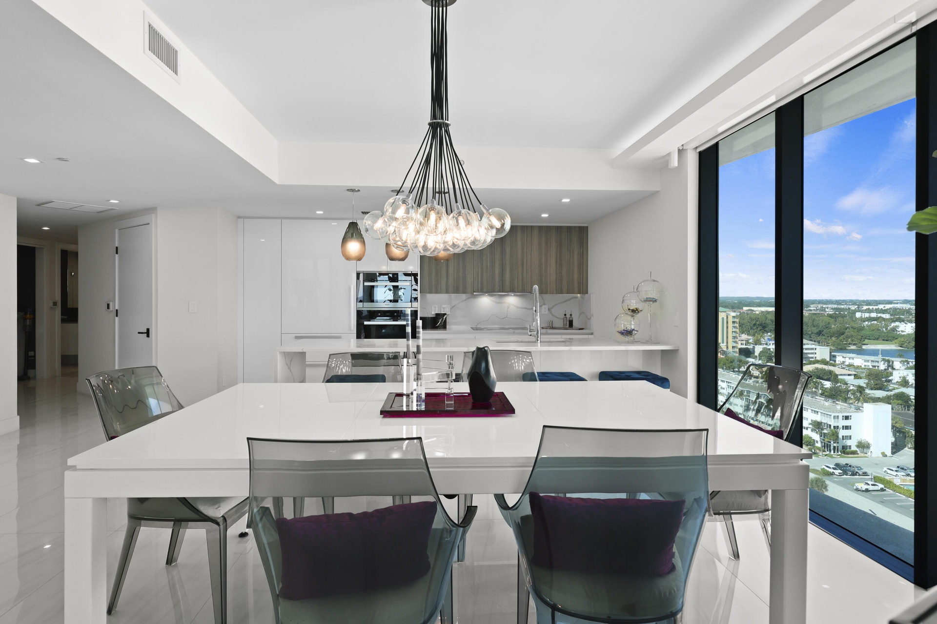 The dining area is illuminated by a designer chandelier and custom accent lighting, all framed by captivating views of the Atlantic Ocean and Intracoa