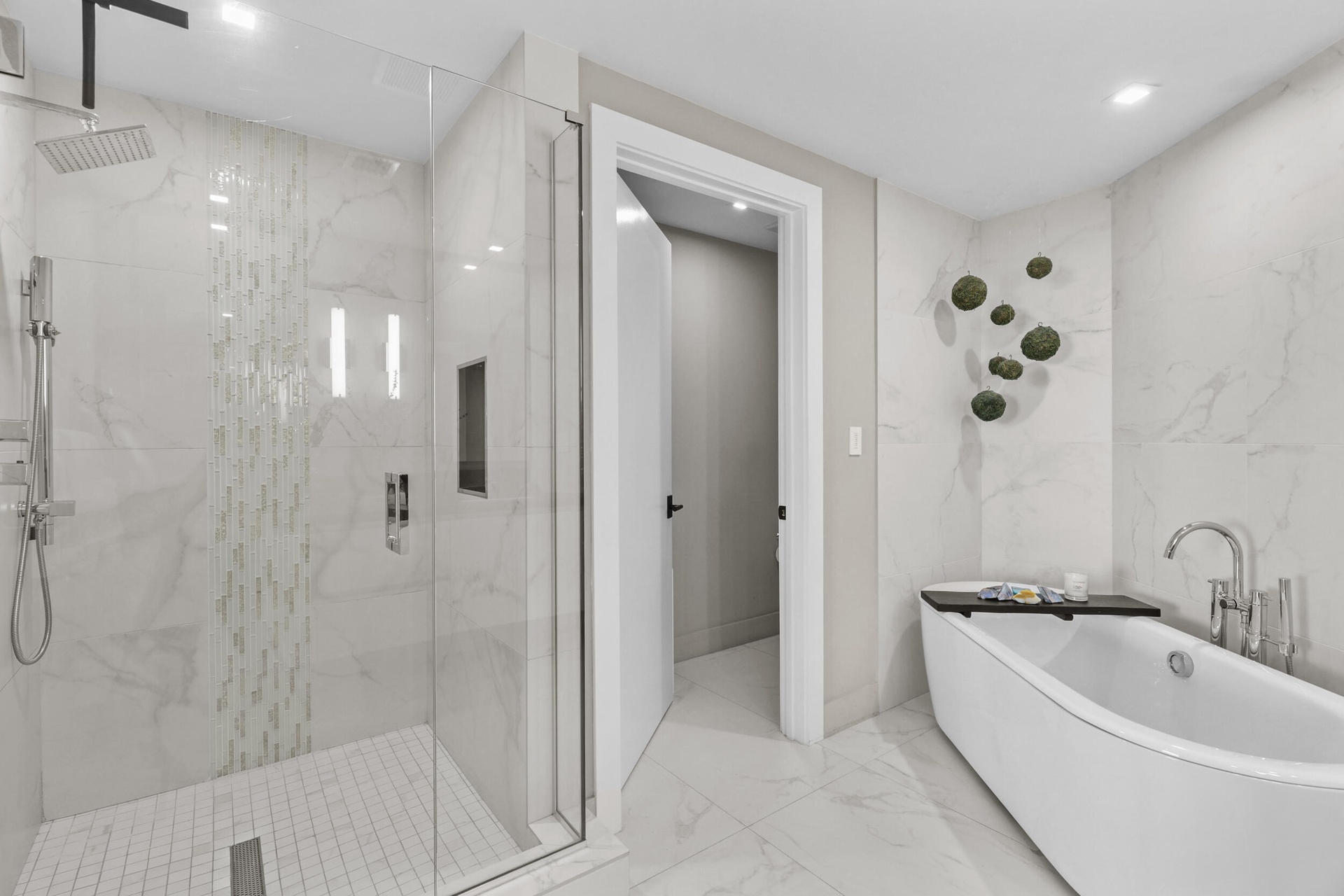 A private spa within the primary suite, this exquisite bathroom showcases custom porcelain tile, a frameless glass shower, a freestanding soaking tub 