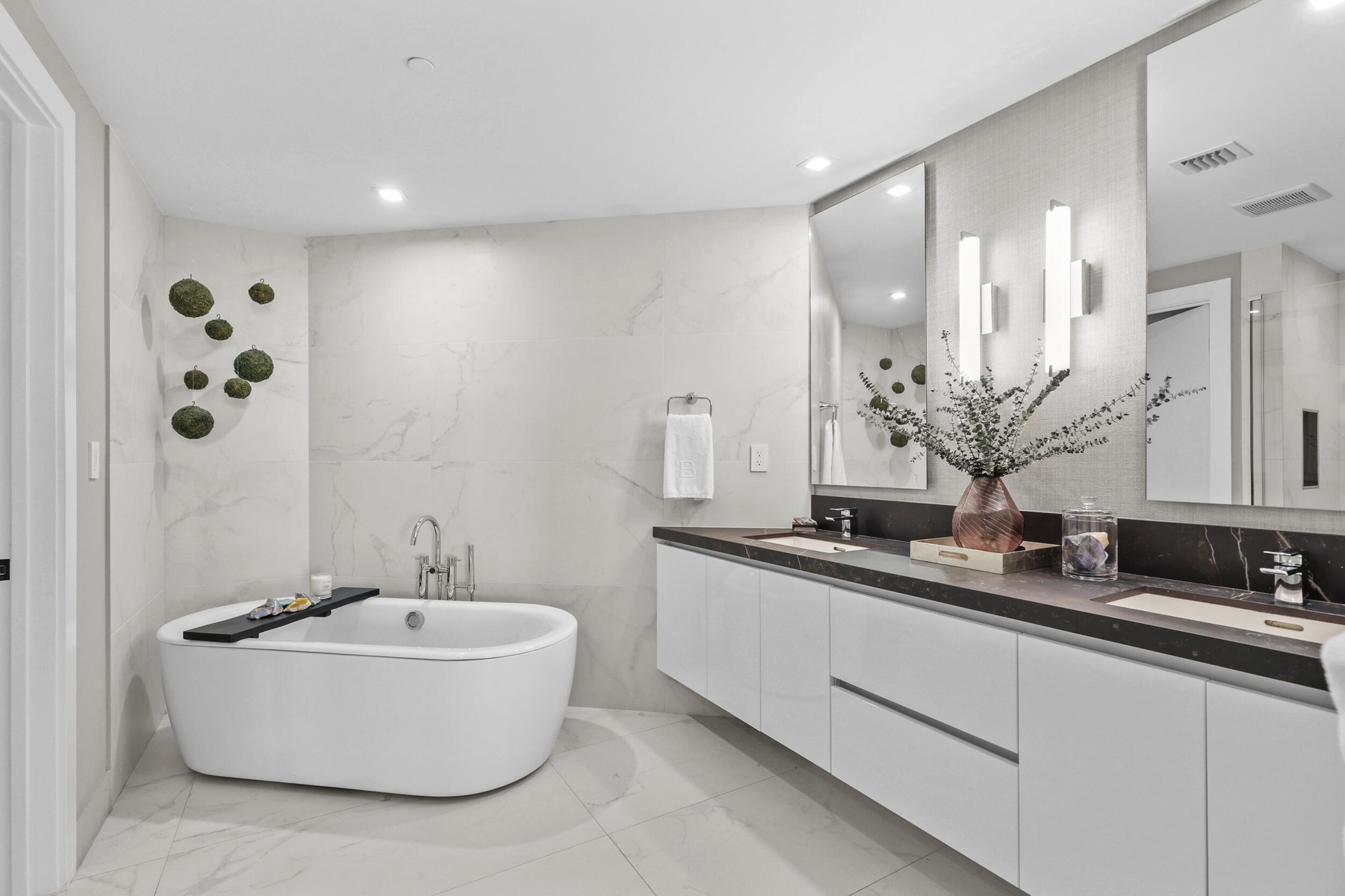 A private spa within the primary suite, this exquisite bathroom showcases custom porcelain tile, a frameless glass shower, a freestanding soaking tub 