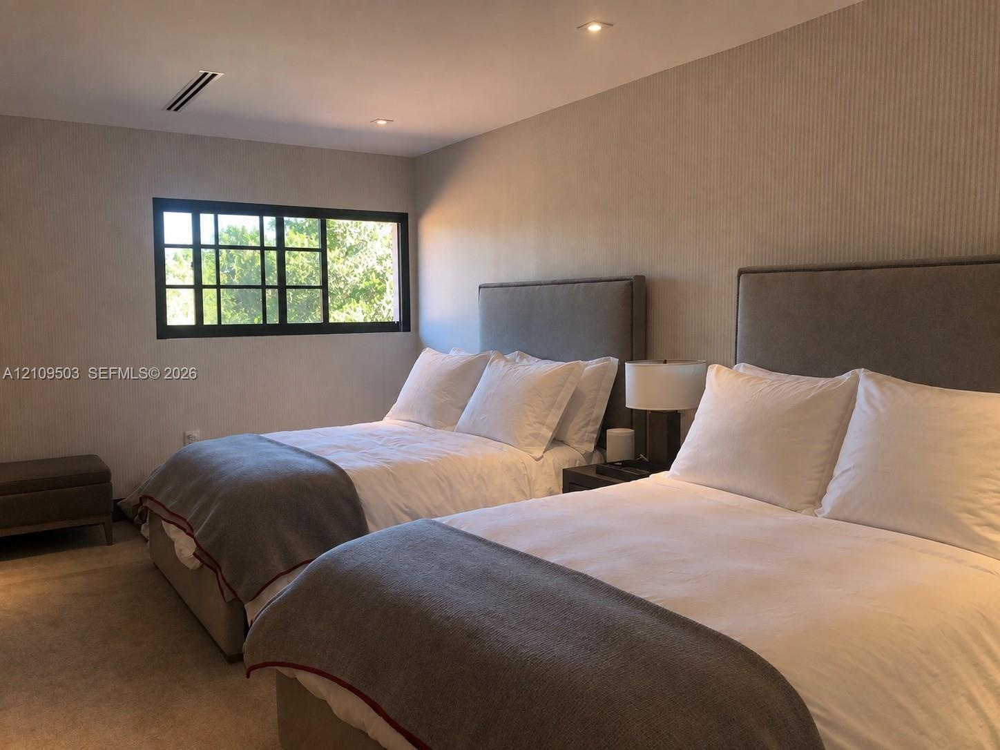 Neutral-toned room featuring recessed ceiling lighting, textured wall coverings, and a multi-pane window with black framing
