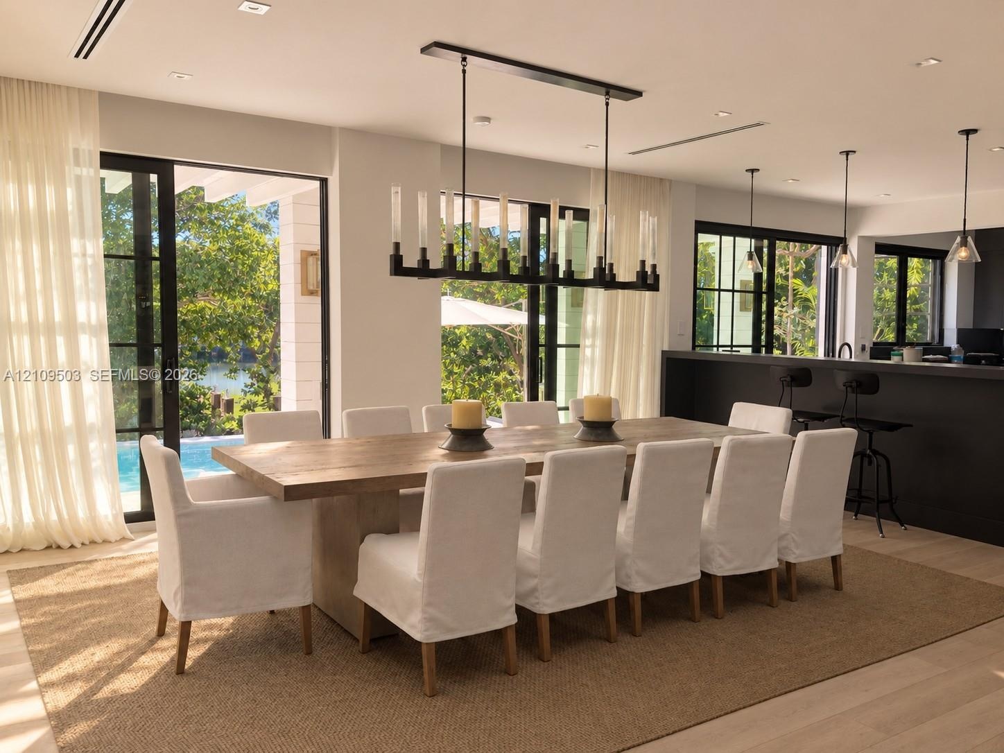 Dining area featuring large-format sliding glass doors, a linear wrought iron chandelier, recessed lighting, wood-finish flooring, and a built-in kitc