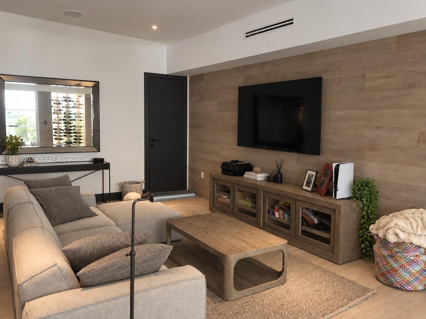 Accent wall with wood-finish paneling, recessed ceiling lighting, and solid core door with matte black hardware