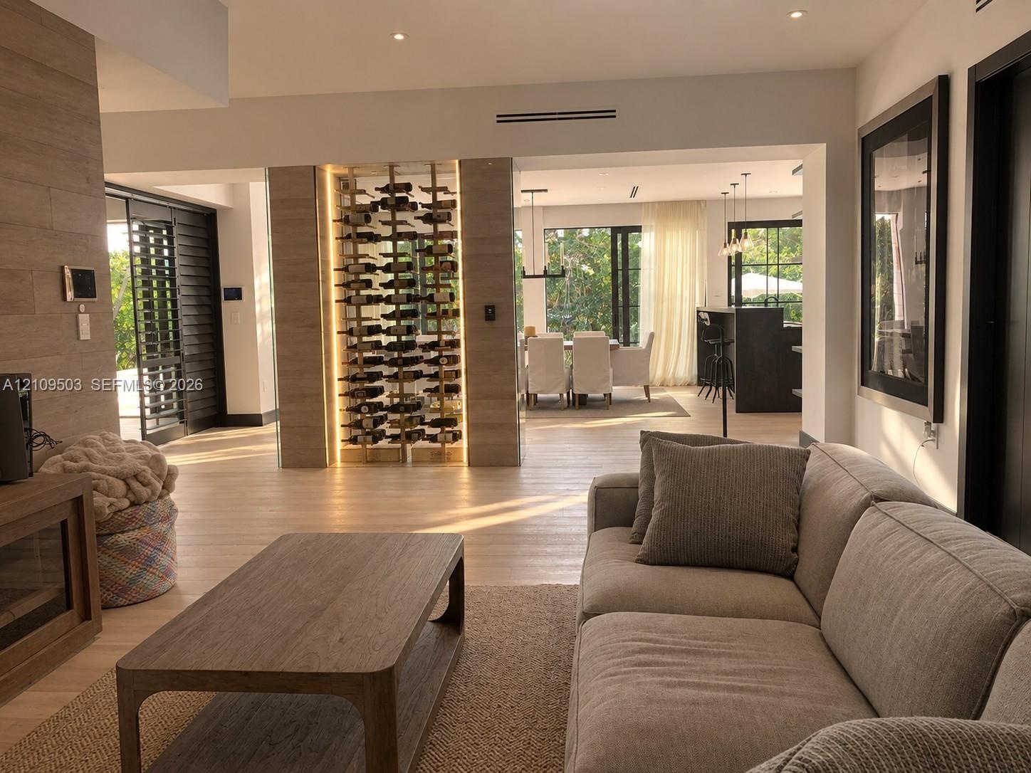 Built-in glass-enclosed wine display with integrated accent lighting, wood-finish flooring, stone-clad feature wall, and recessed ceiling lighting