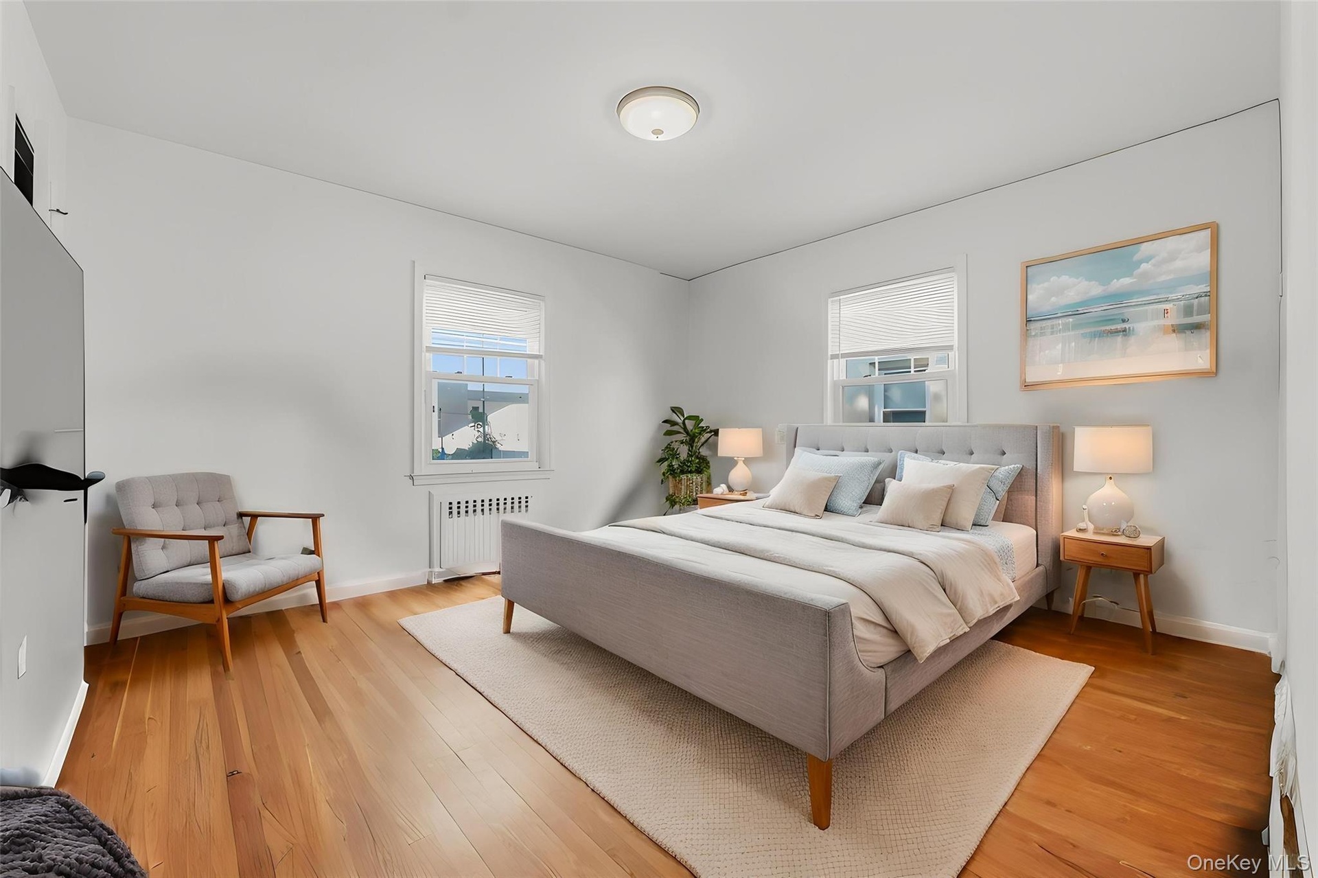 Hardwood flooring throughout, two windows with window treatments, and a ceiling-mounted light fixture