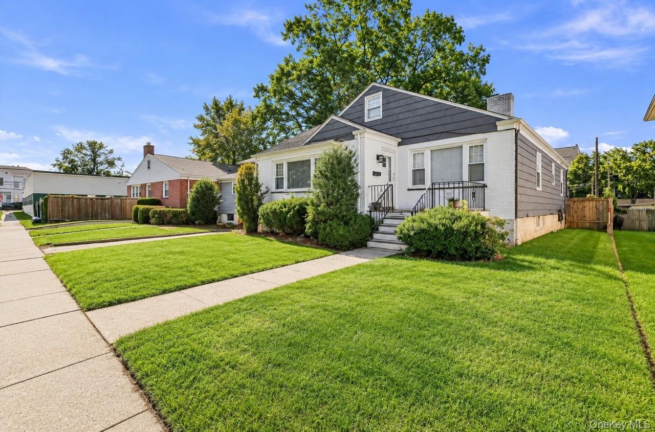 Single-family residence featuring a brick and siding exterior, front porch with metal railings, mature landscaping, and a concrete walkway