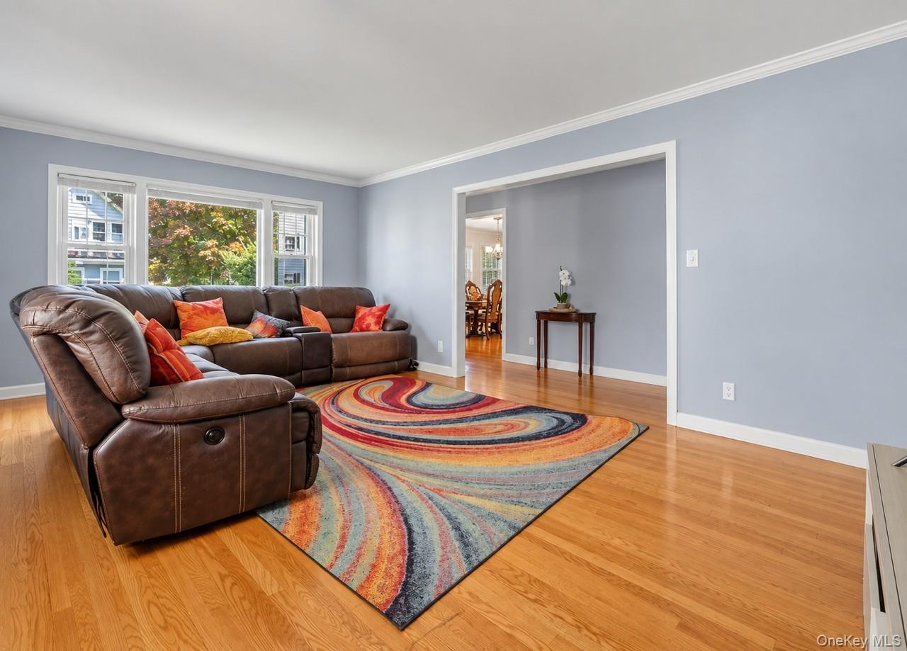 Hardwood flooring, crown molding, wide baseboards, light blue wall paint, and white trim