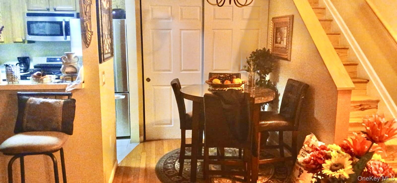 Wood-finish flooring, stainless steel kitchen appliances, dual-panel closet doors, and hardwood staircase with matching handrail