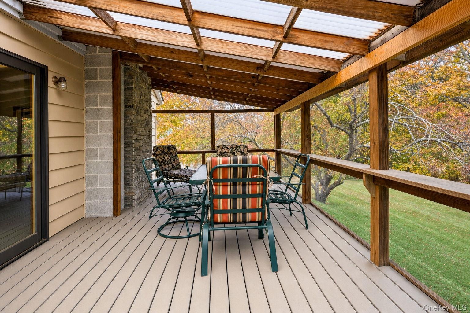 Covered deck featuring composite decking, a timber-framed translucent roof, and screening