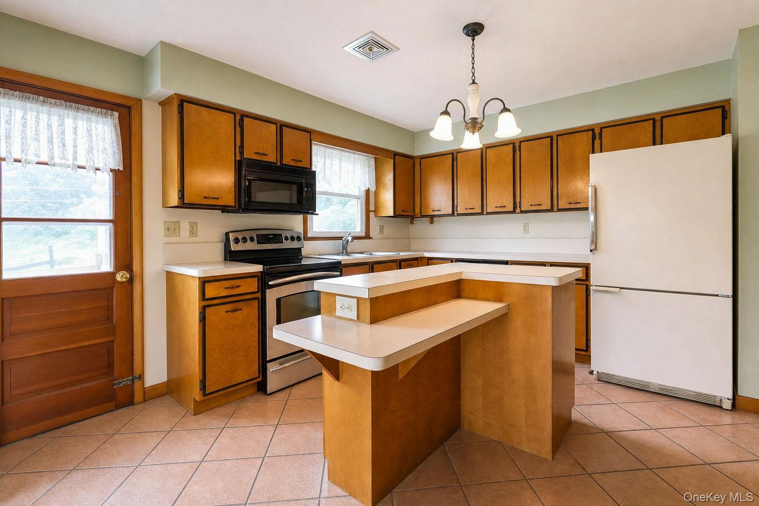 Kitchen featuring wood cabinetry, solid surface countertops, a 2-tiered island with breakfast bar seating, tile flooring, and a glass-paneled exterior