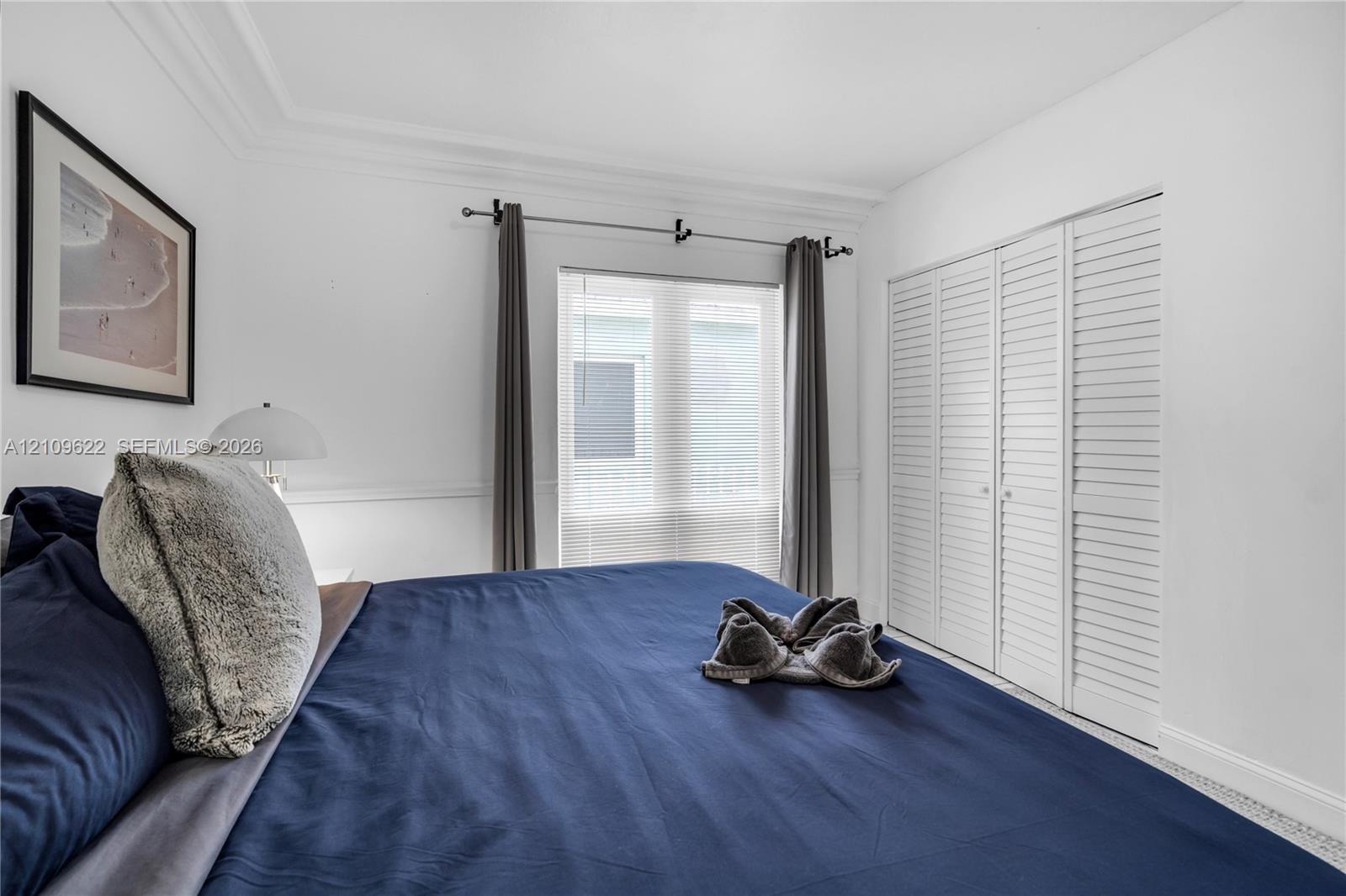 Bedroom featuring white walls, crown molding, chair rail trim, and a multi-panel closet with louvered doors