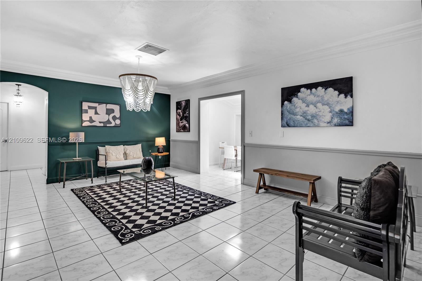 Interior room featuring large-format tile flooring, crown molding, chair rail trim, and a multi-tiered beaded pendant light fixture