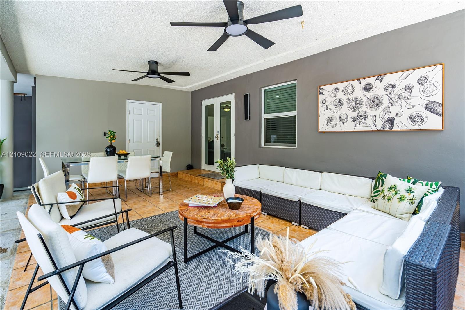 Covered patio featuring ceramic tile flooring, dual ceiling fans, and glass-paned double doors