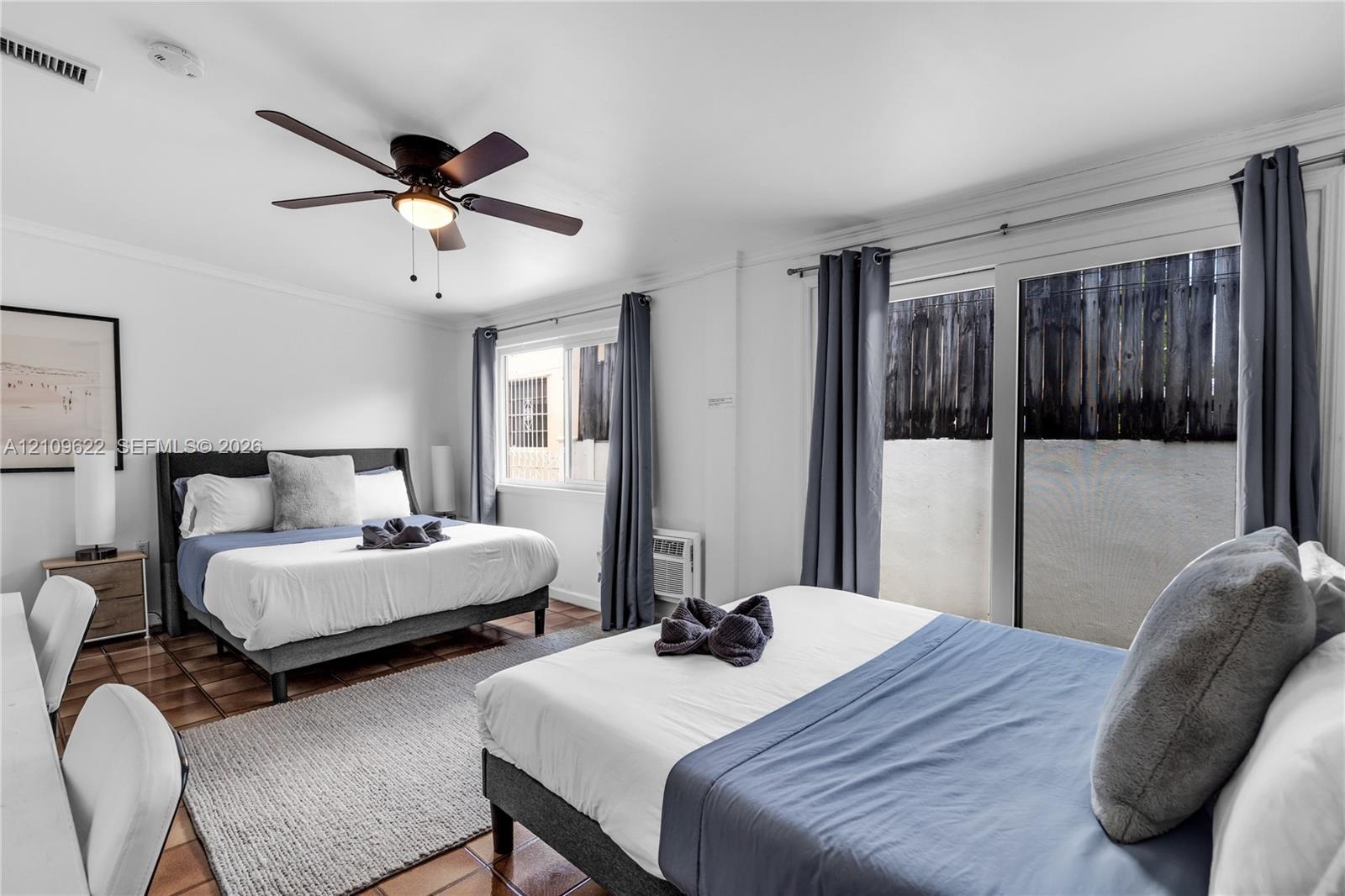 Room featuring tile flooring, a multi-blade ceiling fan, sliding glass doors, and dual-pane windows