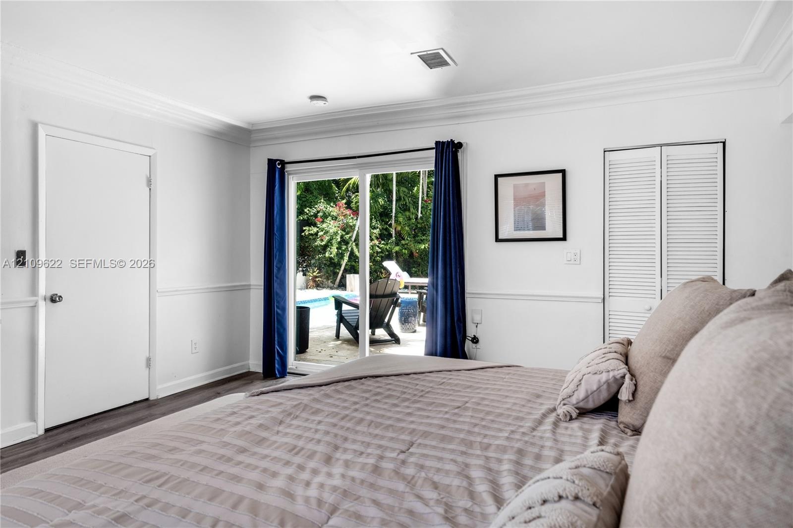 Interior space featuring crown molding, wainscoting, wood-finish flooring, and sliding glass doors with direct access to an outdoor area