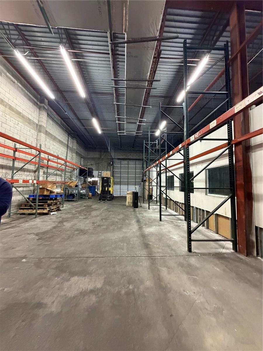 Industrial warehouse space featuring high ceilings, exposed structural steel, heavy-duty industrial racking, concrete flooring, and linear overhead li