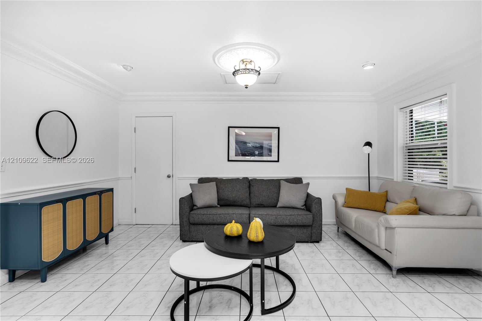 Bright interior featuring white tile flooring, decorative chair rail molding, crown molding, and a central ceiling light fixture with a medallion