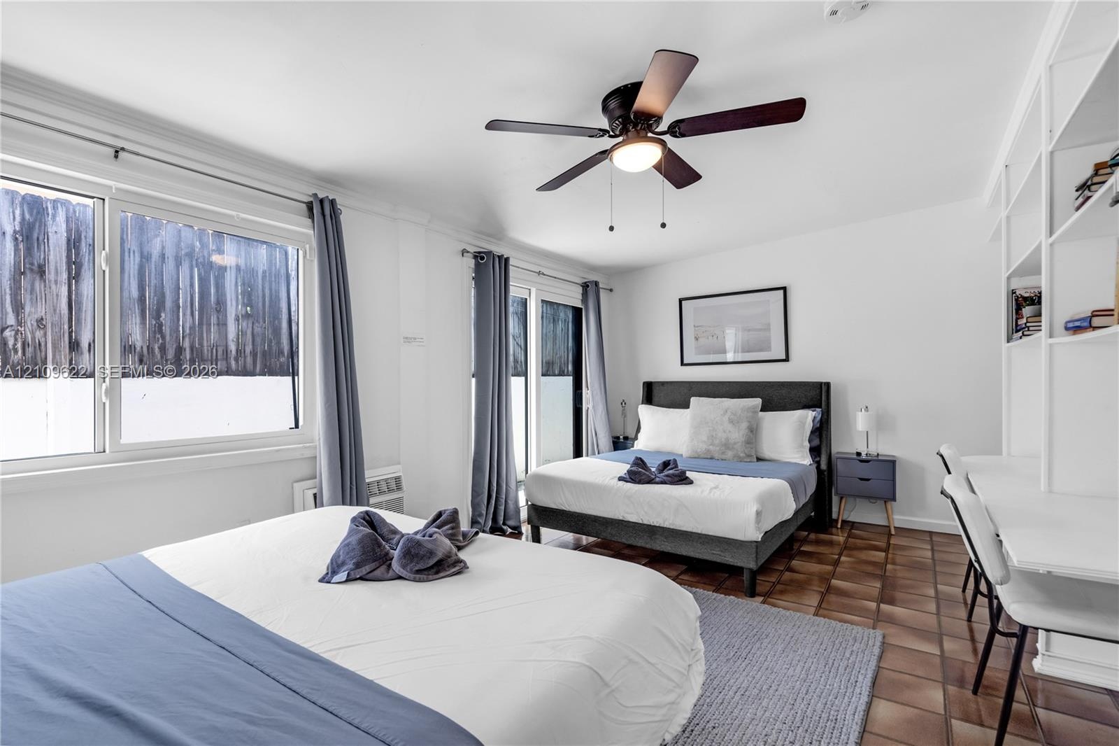 Bedroom featuring tile flooring, built-in shelving, a ceiling fan, and large windows with sliding door access to exterior space