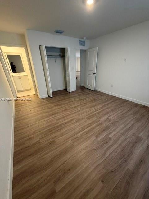 Wood-finish flooring, neutral wall tones, interior closet with shelving, and multi-panel interior door