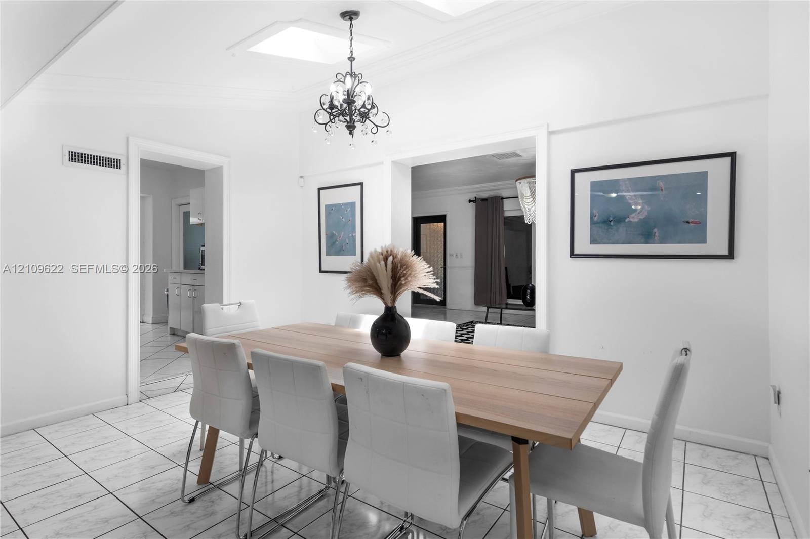 Interior space featuring light-toned tile flooring, recessed ceiling lighting, and a decorative wrought iron chandelier