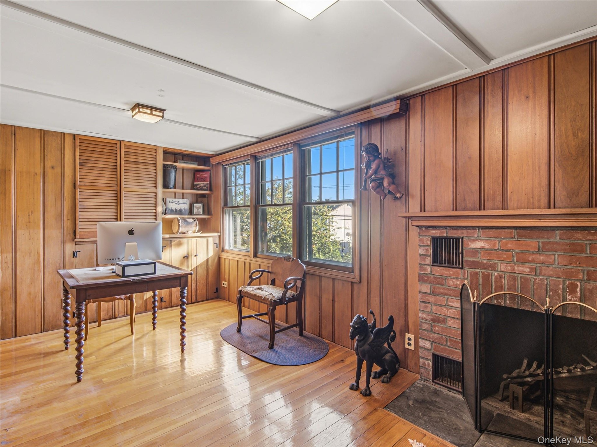 Bedroom or office space with hardwood floors and a wood-burning fireplace.