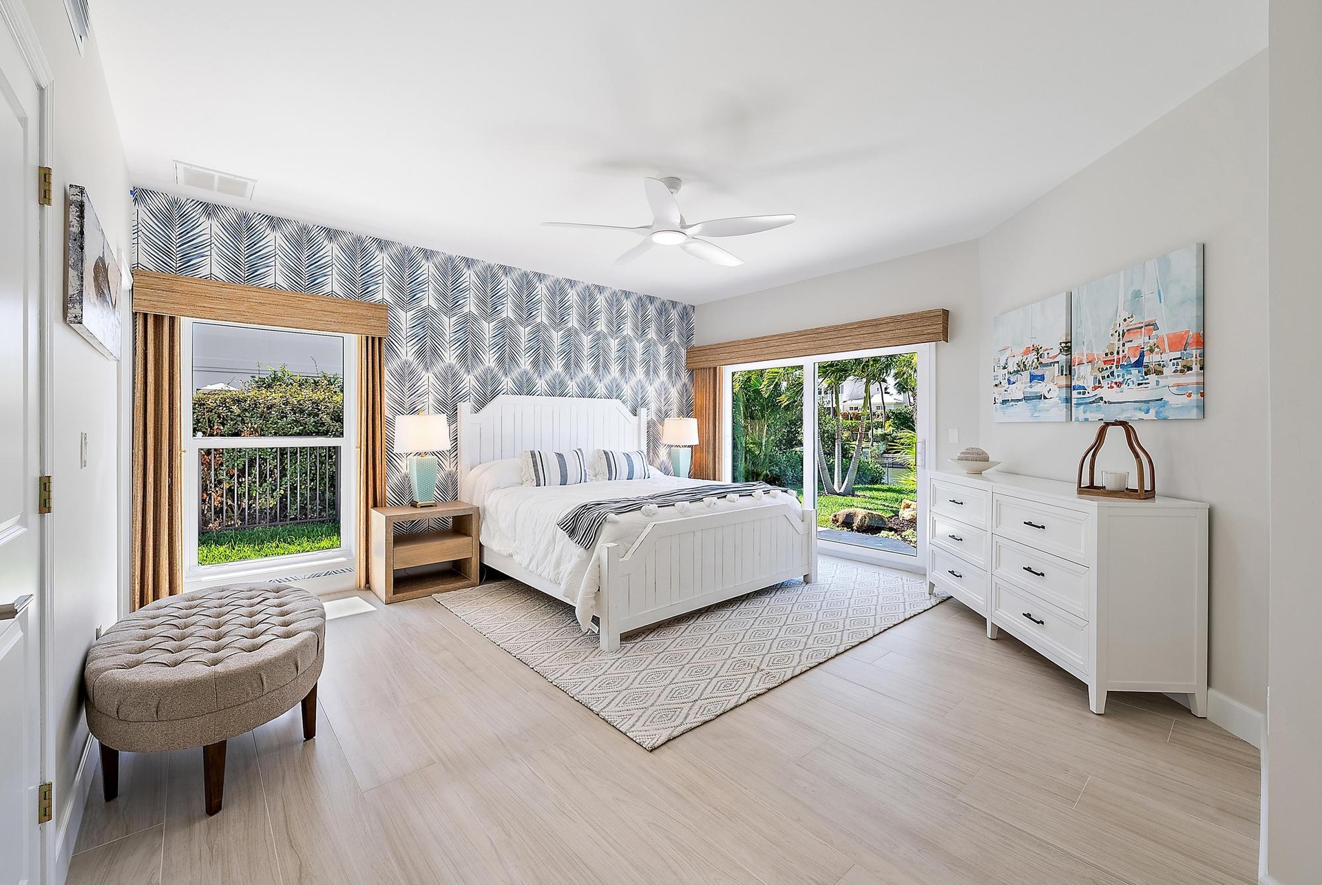Room featuring wood-finish flooring, accent wallpaper, a ceiling fan, and sliding glass doors providing outdoor access