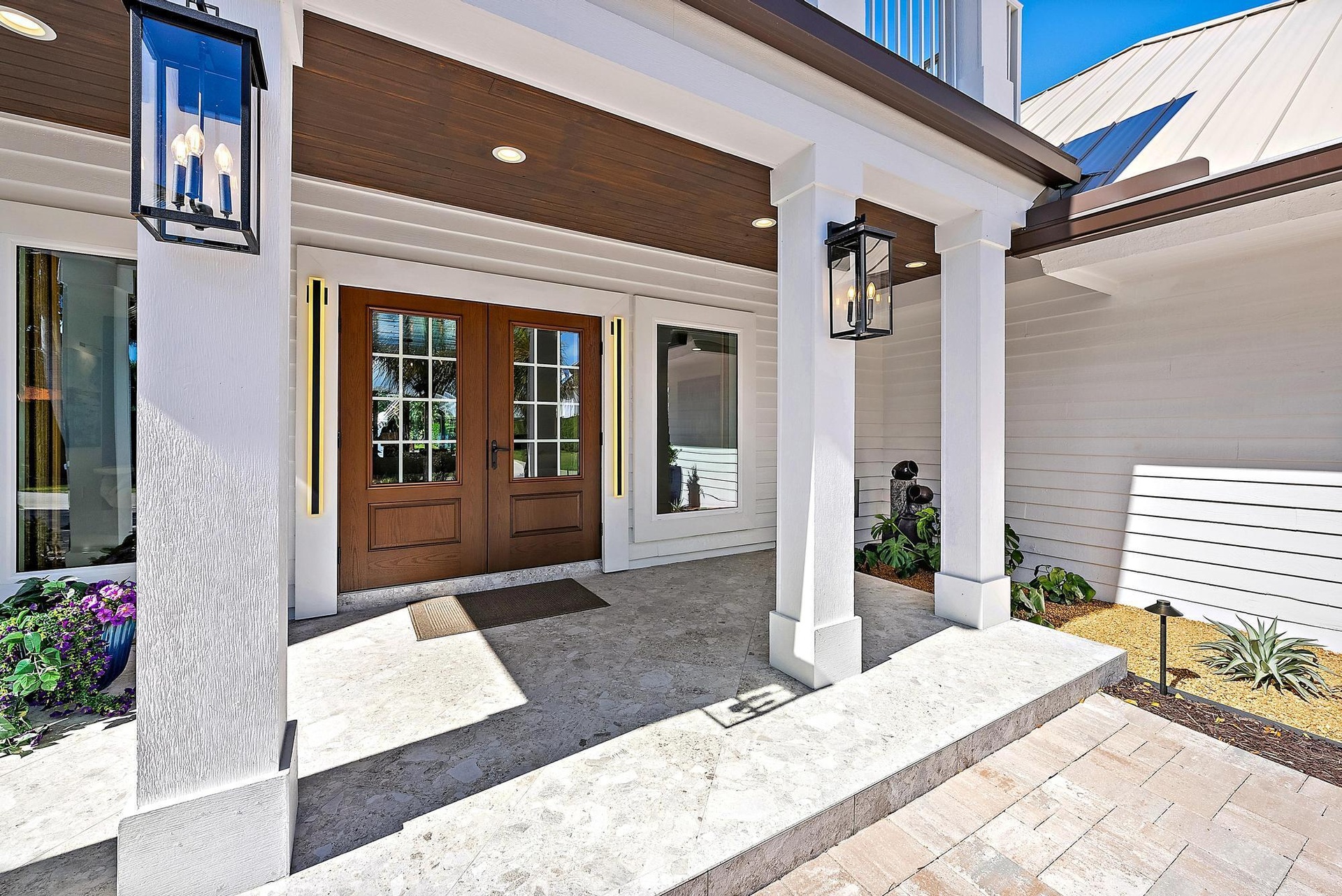 Covered entryway featuring horizontal lap siding, double wood-frame doors with glass panes, wood-finish ceiling cladding, stone flooring, and metal la