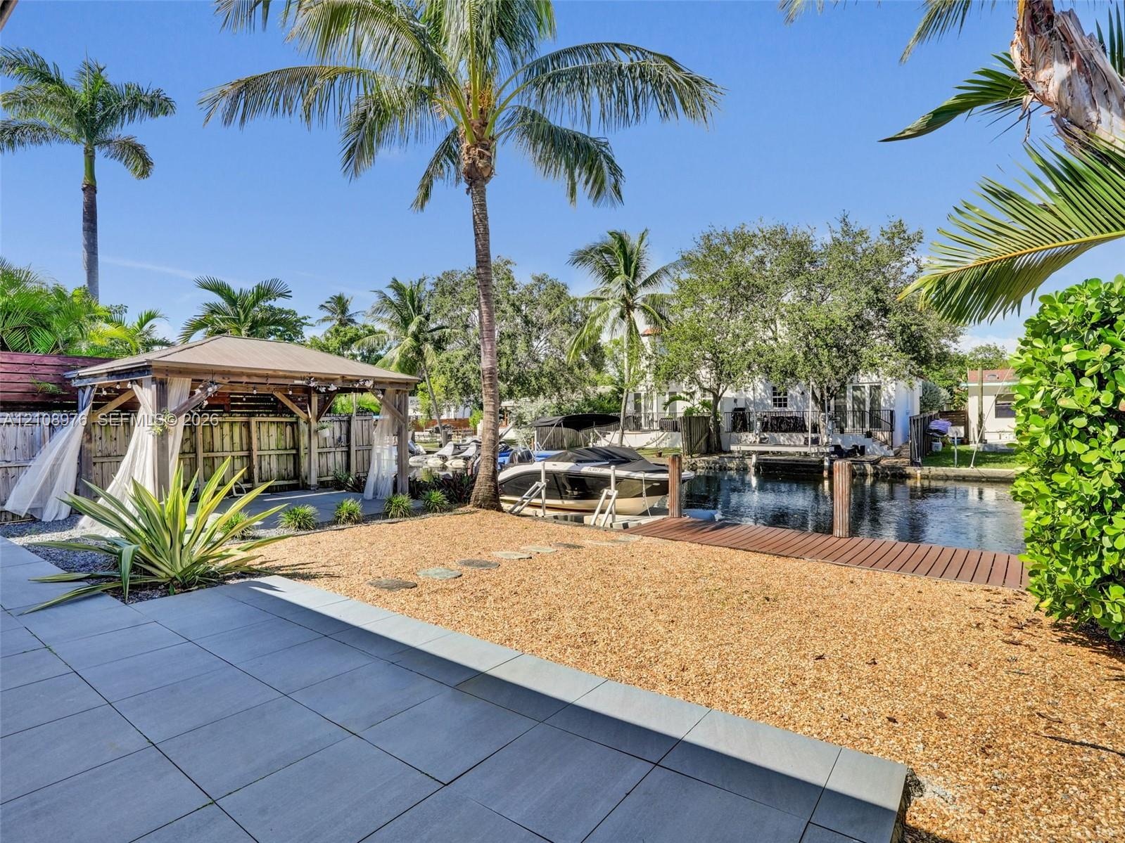 Waterfront grounds featuring a permanent timber-frame gazebo, with space for a summer kitchen and living are, a private dock, gravel hardscaping, and 
