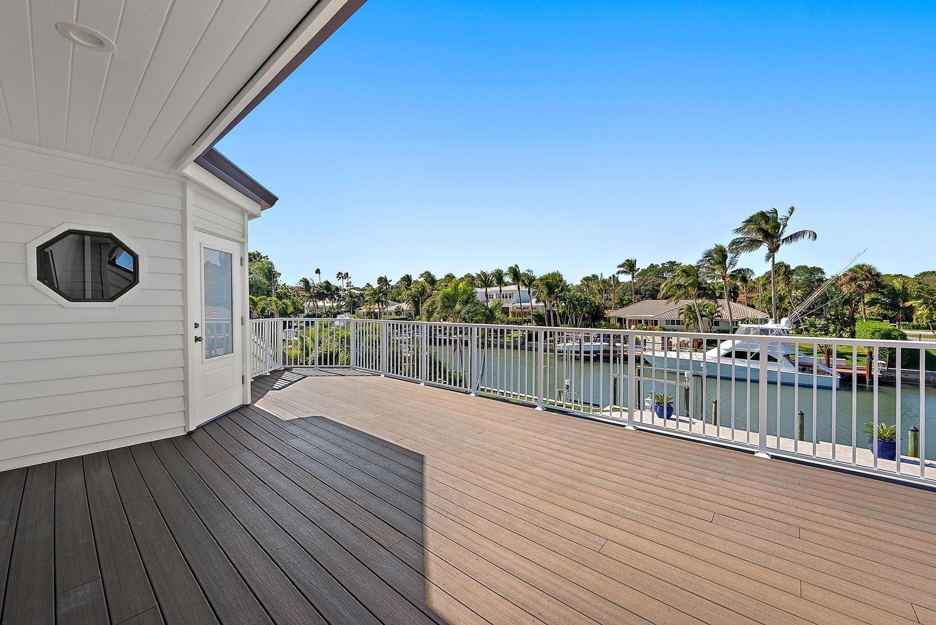 Expansive wood-finish deck featuring a white metal railing, recessed ceiling lighting, and horizontal siding