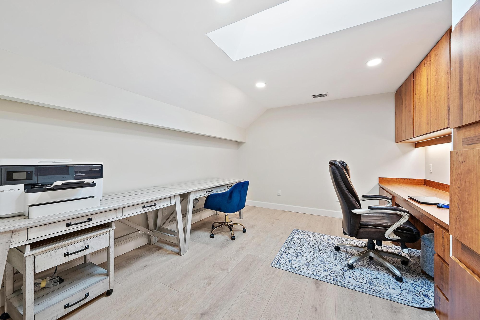 Skylight, wood-finish flooring, recessed lighting, and wall-to-wall built-in cabinetry with under-cabinet lighting