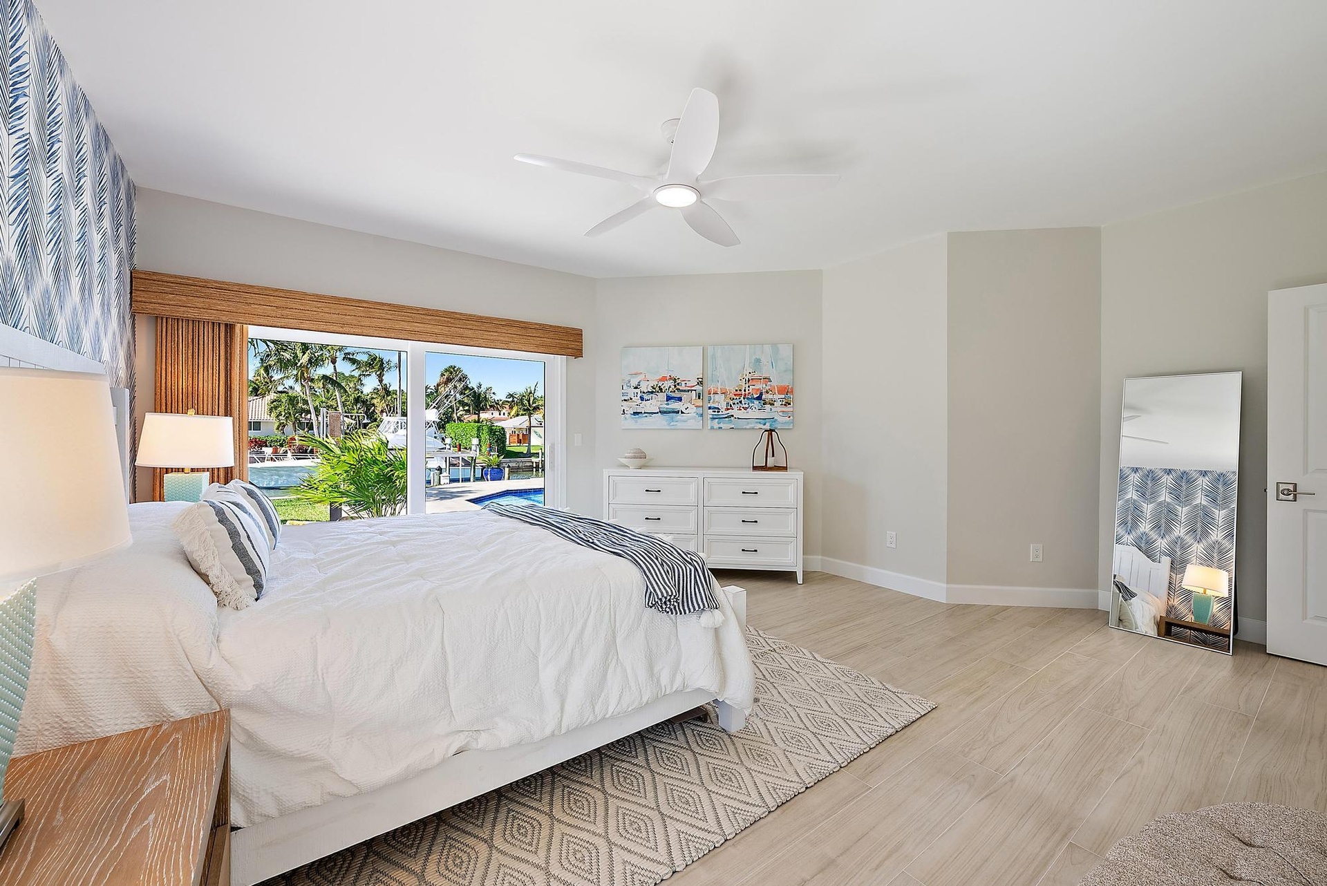 Large sliding glass door featuring integrated bamboo-finish valance, wood-finish flooring, and white multi-blade ceiling fan with light fixture