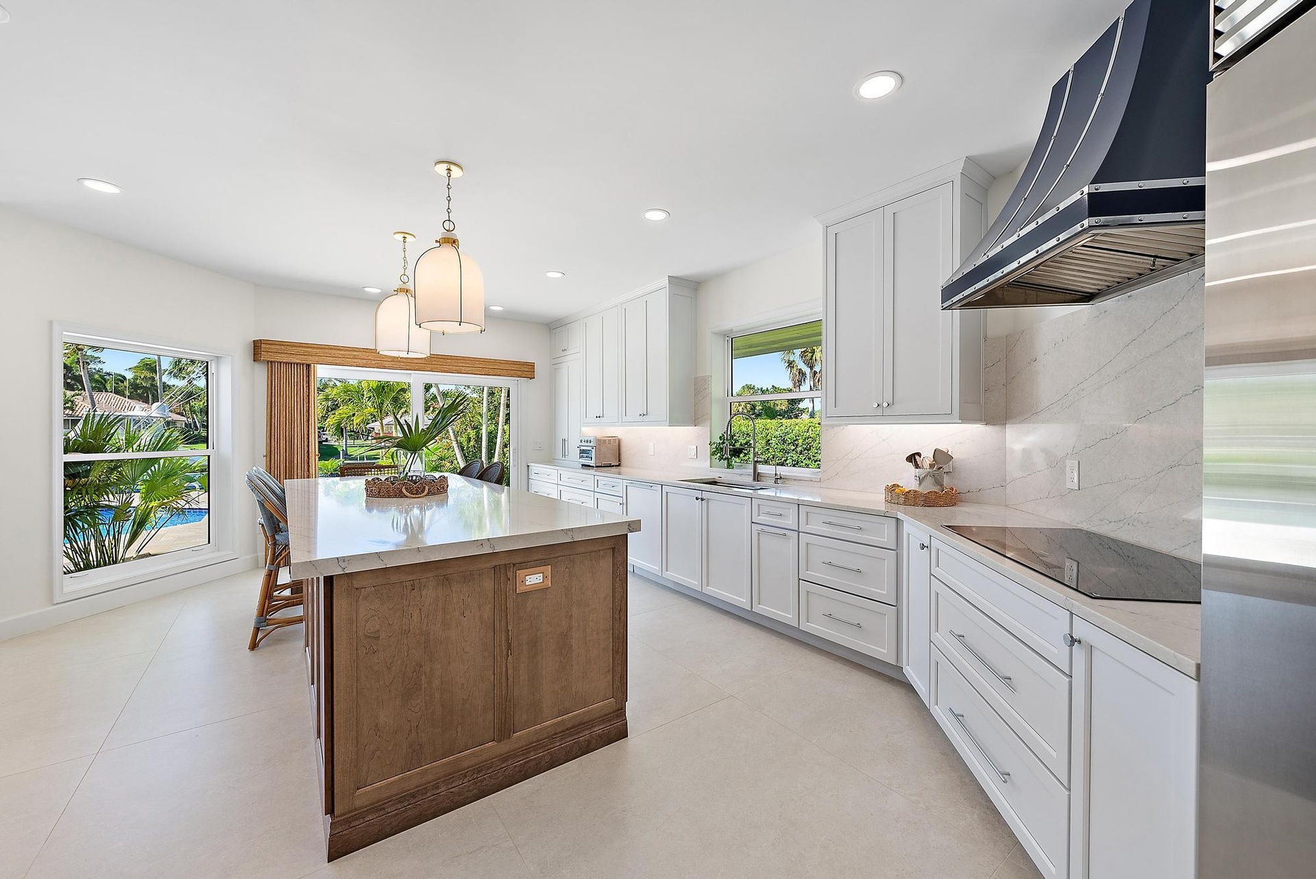 Kitchen featuring a central island with wood-finish cabinetry, quartz countertops, white Shaker-style cabinetry, a custom metal range hood, and recess