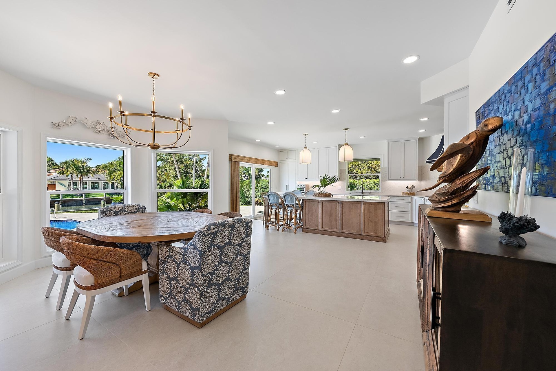 Open-concept kitchen and dining area featuring large-format tile flooring, a multi-tone kitchen island, white shaker-style cabinetry, and a circular m